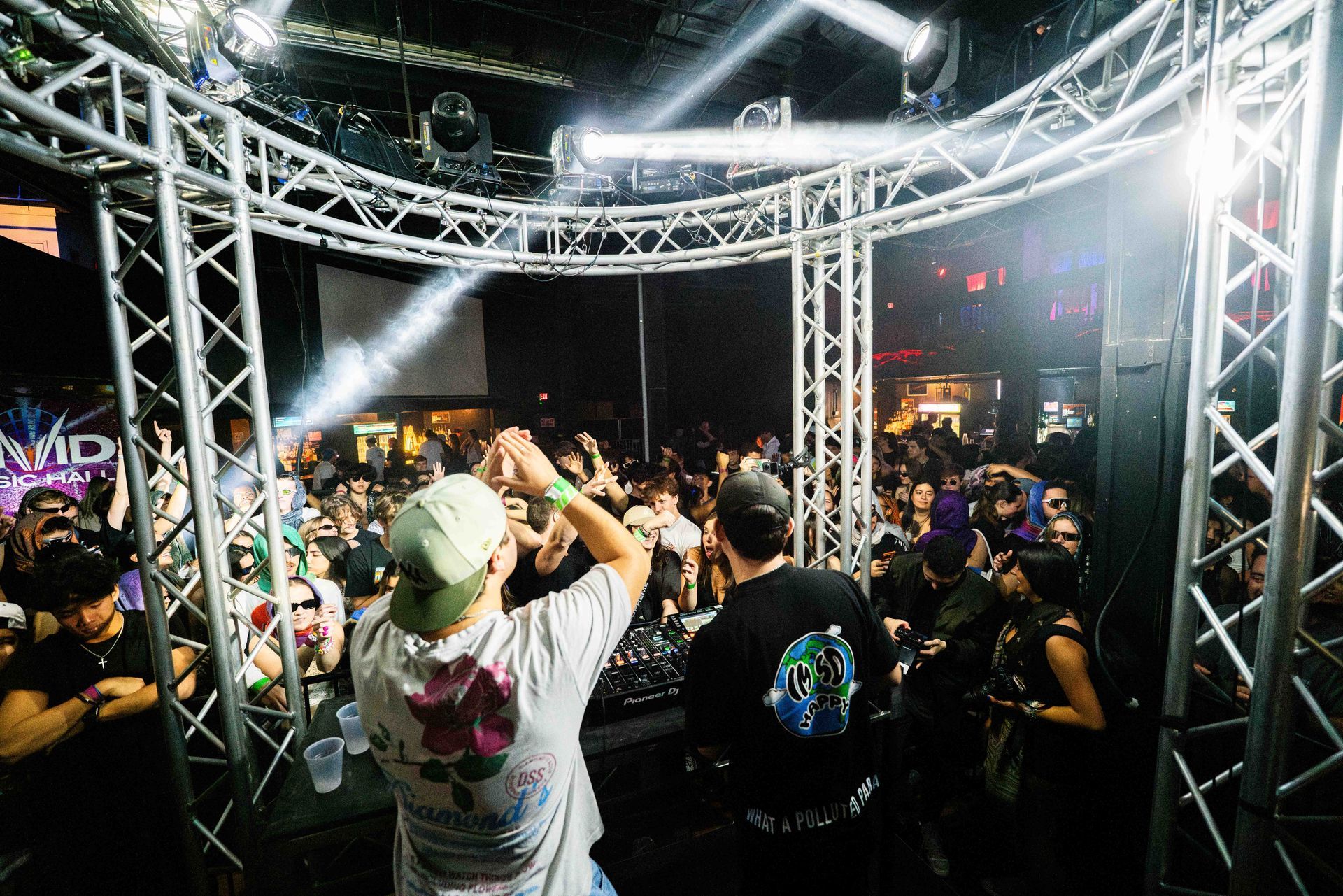 A man is playing a dj set in front of a crowd at a party.