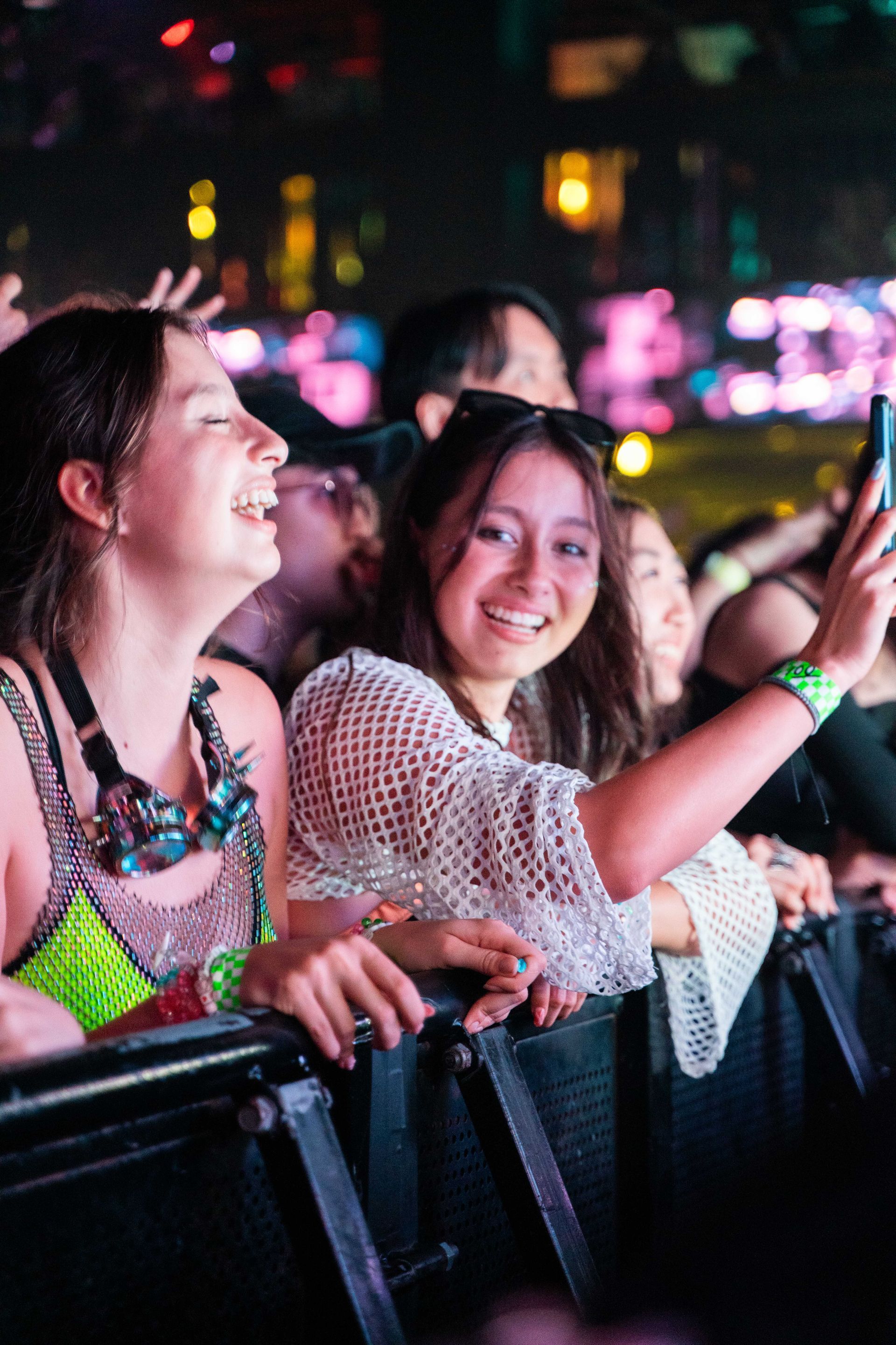 A group of people are sitting in a row at a concert taking a selfie.