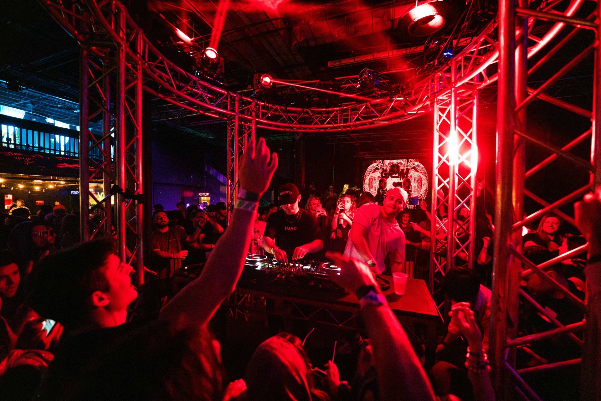 A crowd of people are dancing in a dark room with red lights
