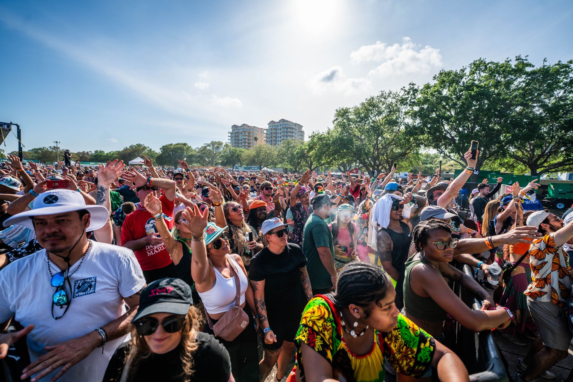 A large crowd of people are dancing at a music festival.