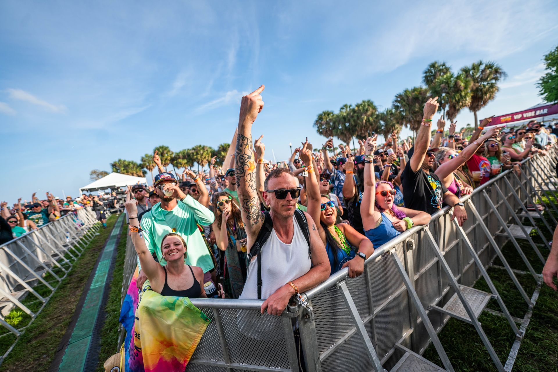 A crowd of people are standing in front of a fence at a concert.