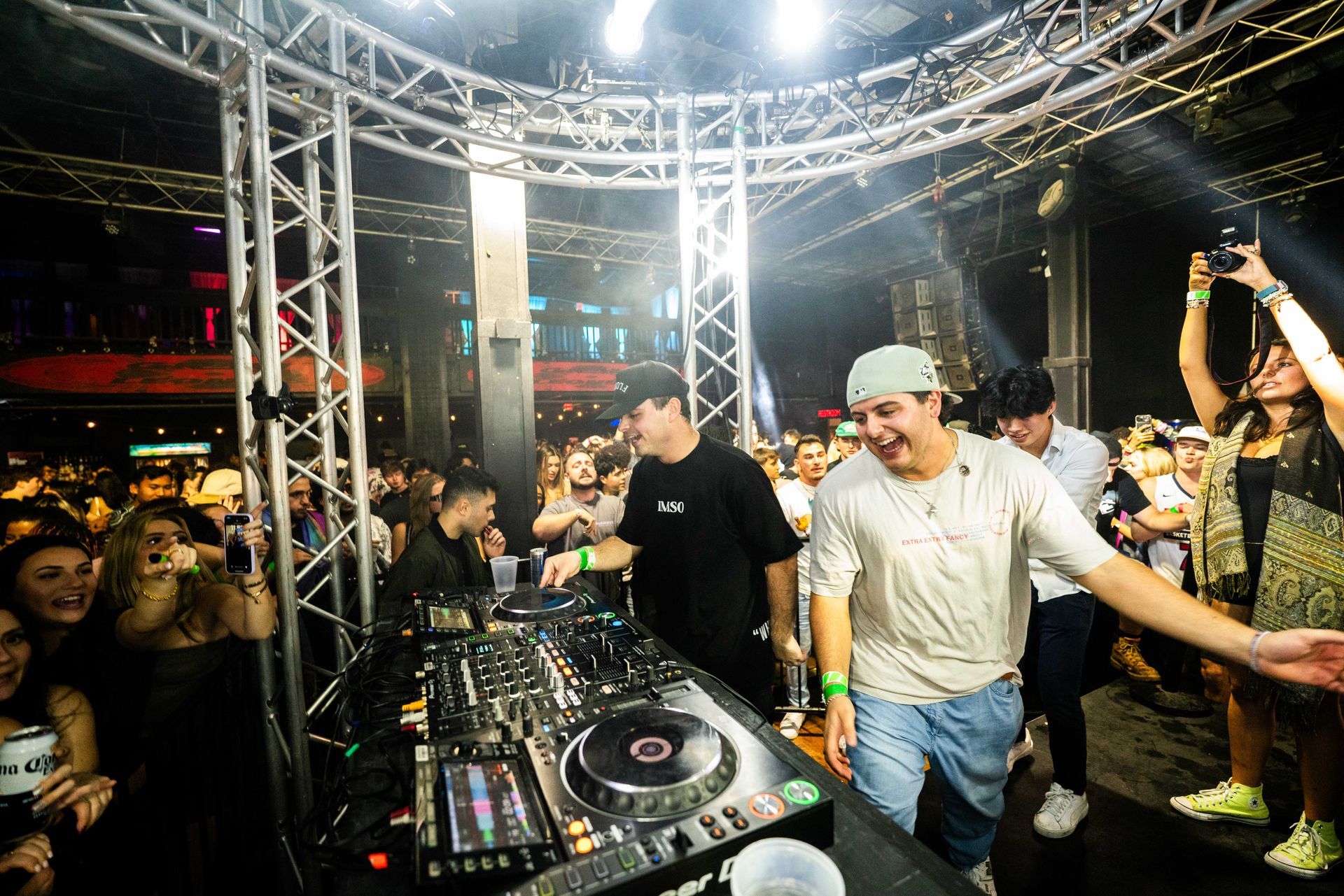 A group of people are standing around a dj booth at a party.