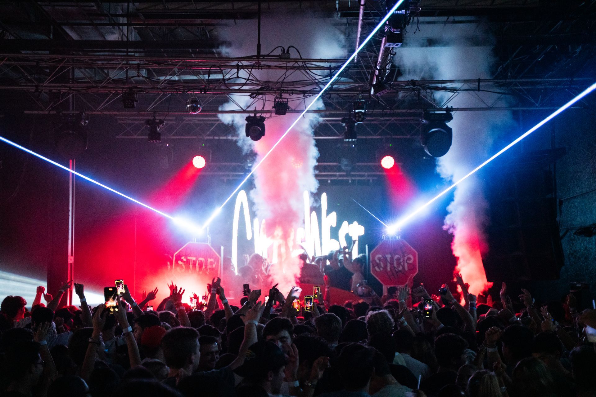 A crowd of people at a concert with a stop sign on the stage