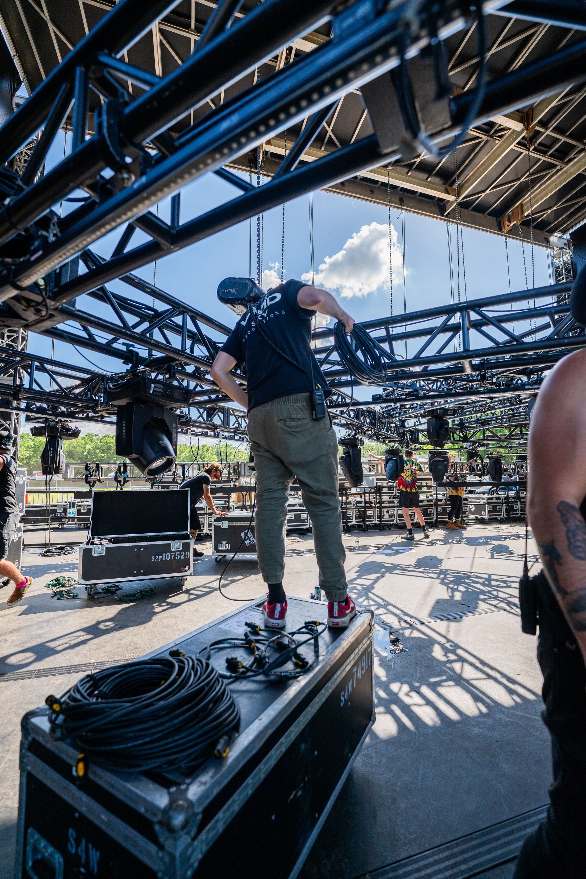 A man is standing on a box under a stage holding a fan.