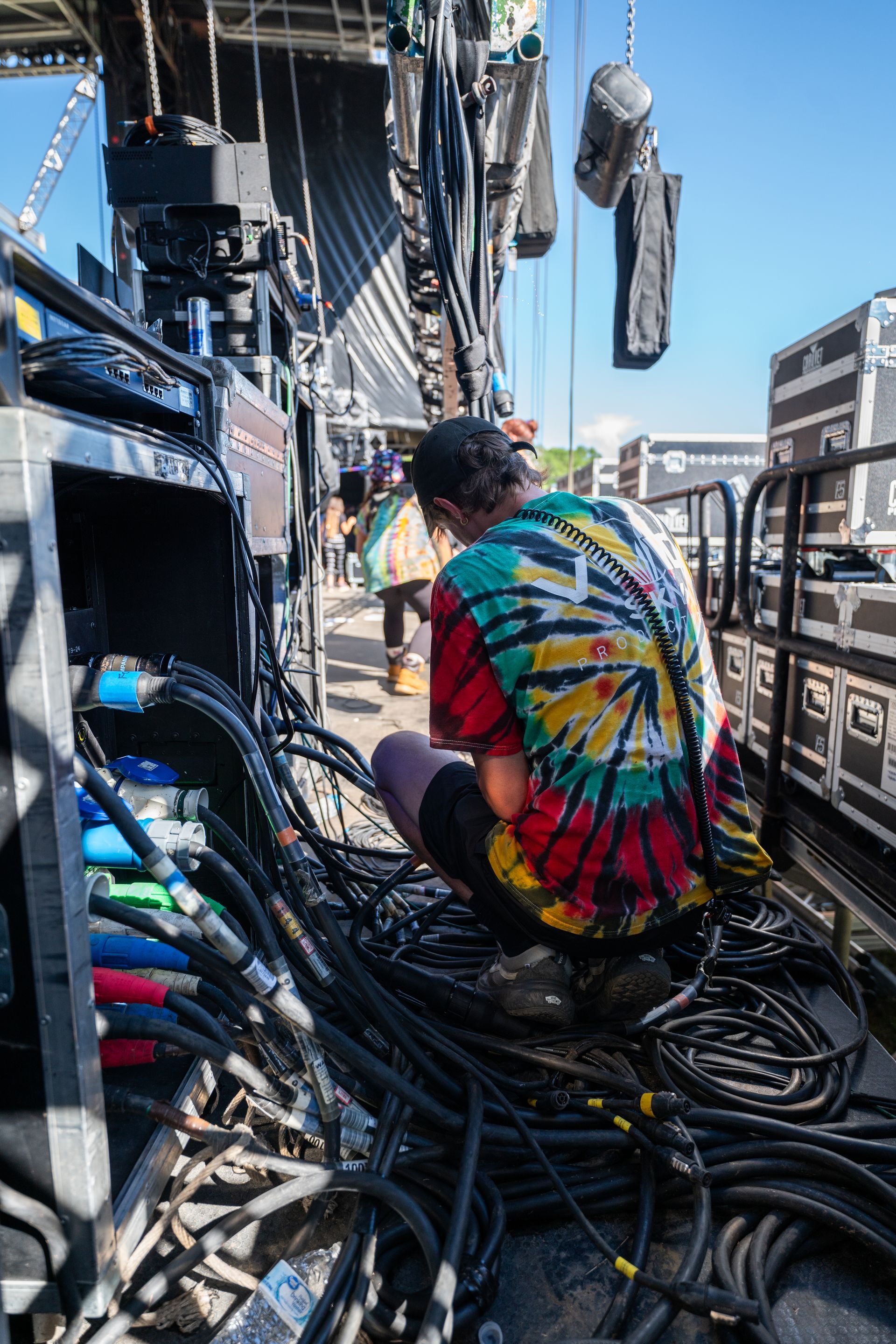 A man is kneeling down in front of a bunch of wires.