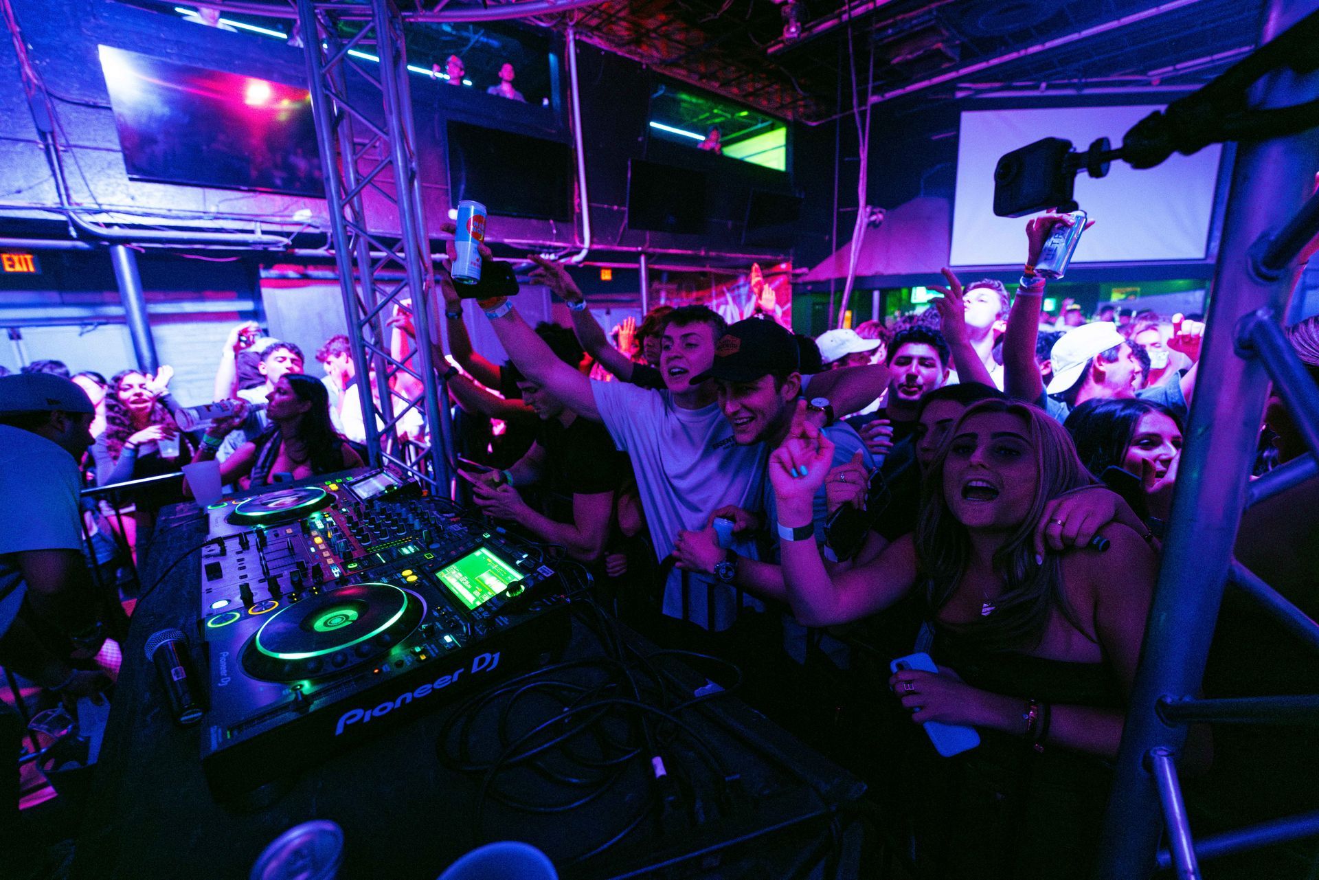 A crowd of people at a party with a pioneer dj