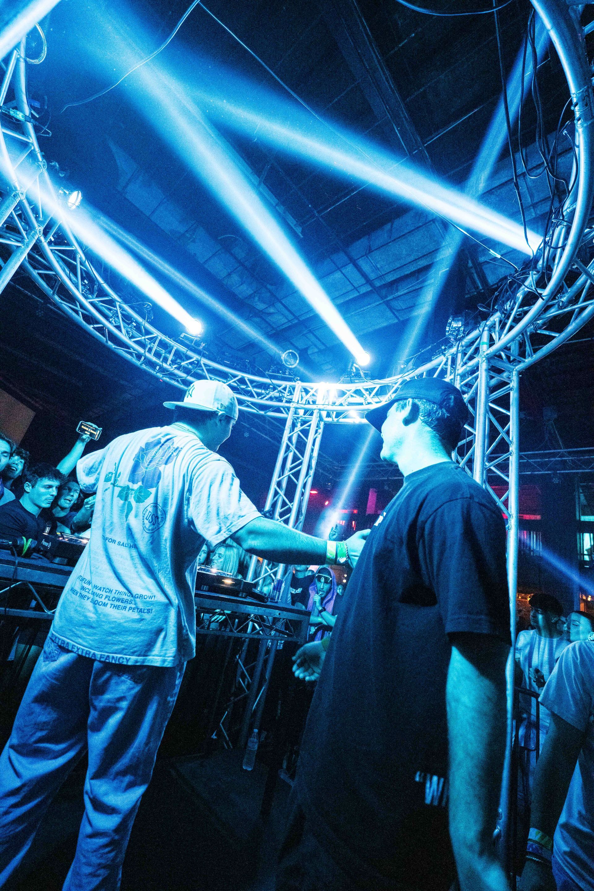 Two men are standing on a stage with blue lights behind them