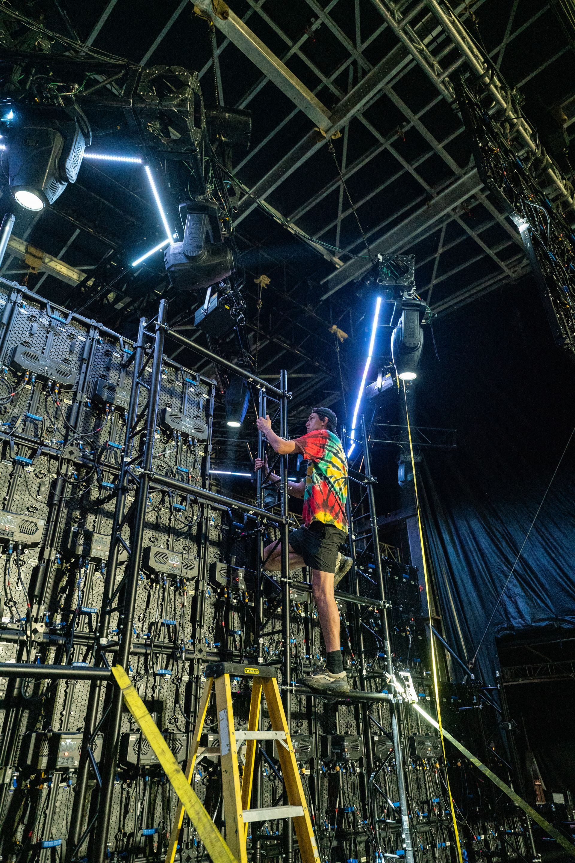 A man is standing on a ladder working on a stage.