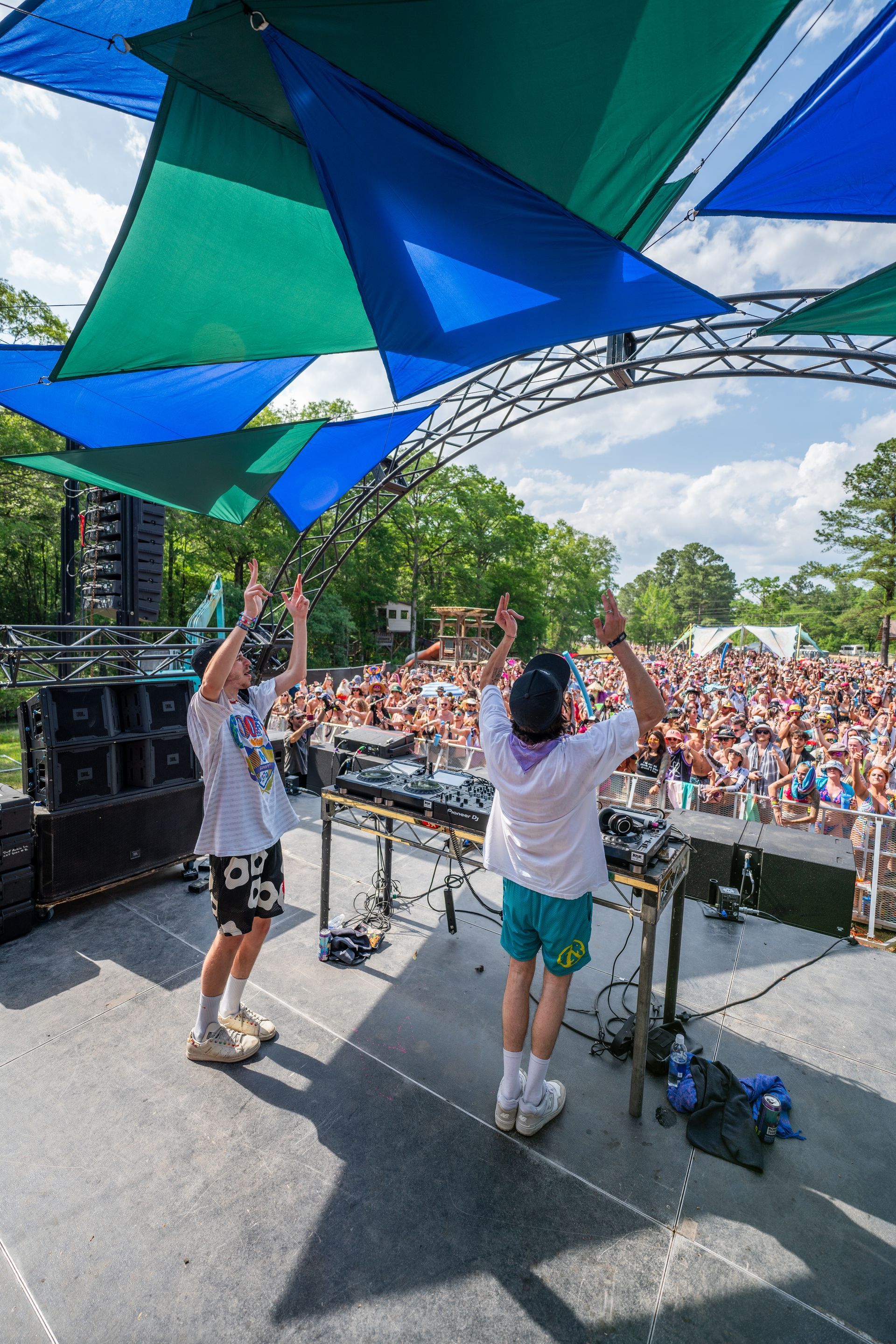 Two men are standing on a stage with their arms in the air.
