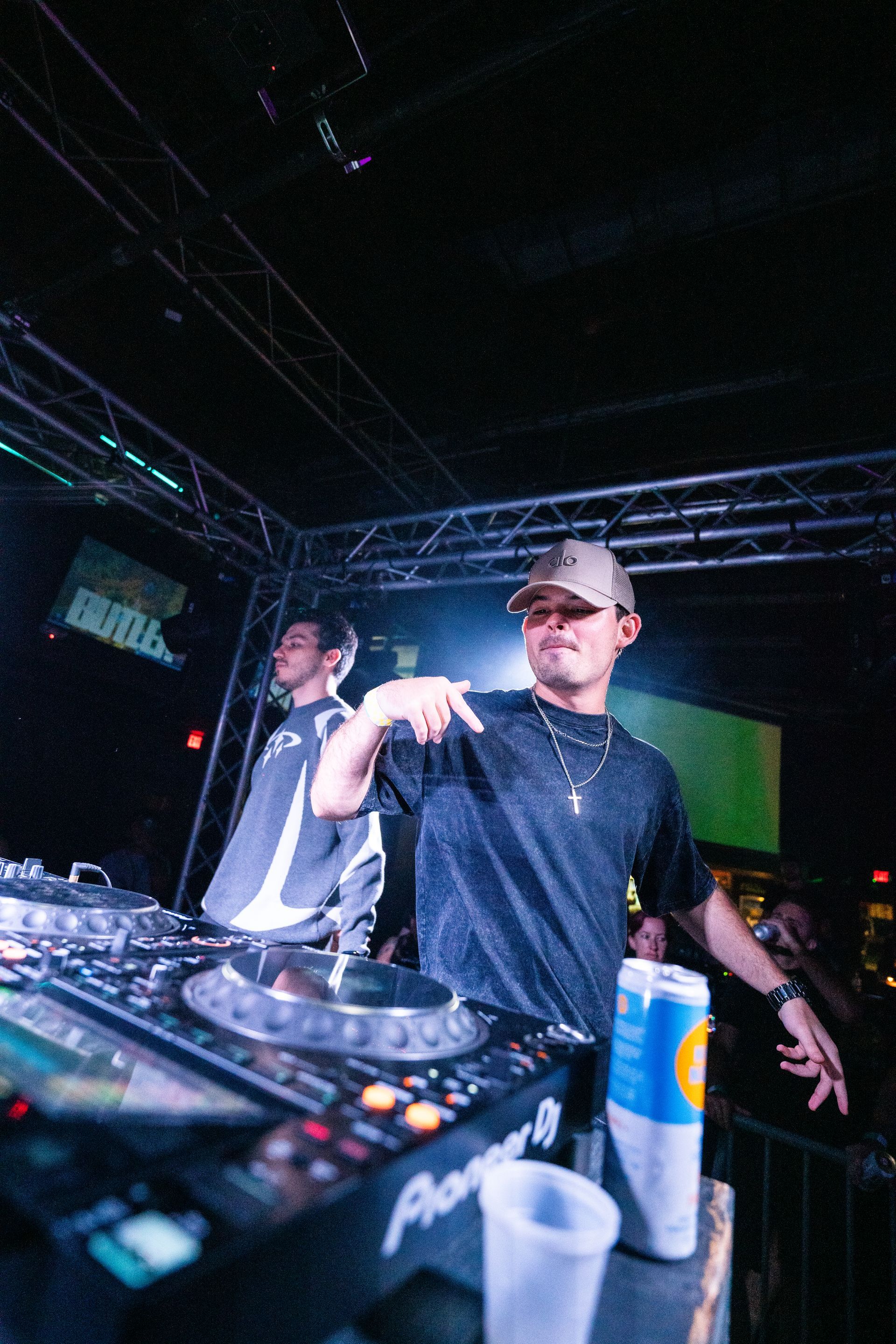 A man is standing in front of a dj mixer in a dark room.