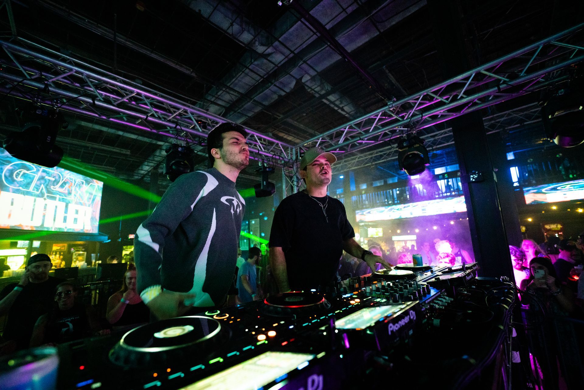 Two men are playing music at a party in a club.