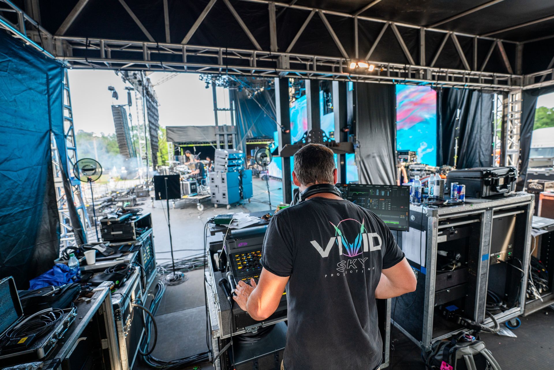 A man in a black shirt is standing in front of a stage.