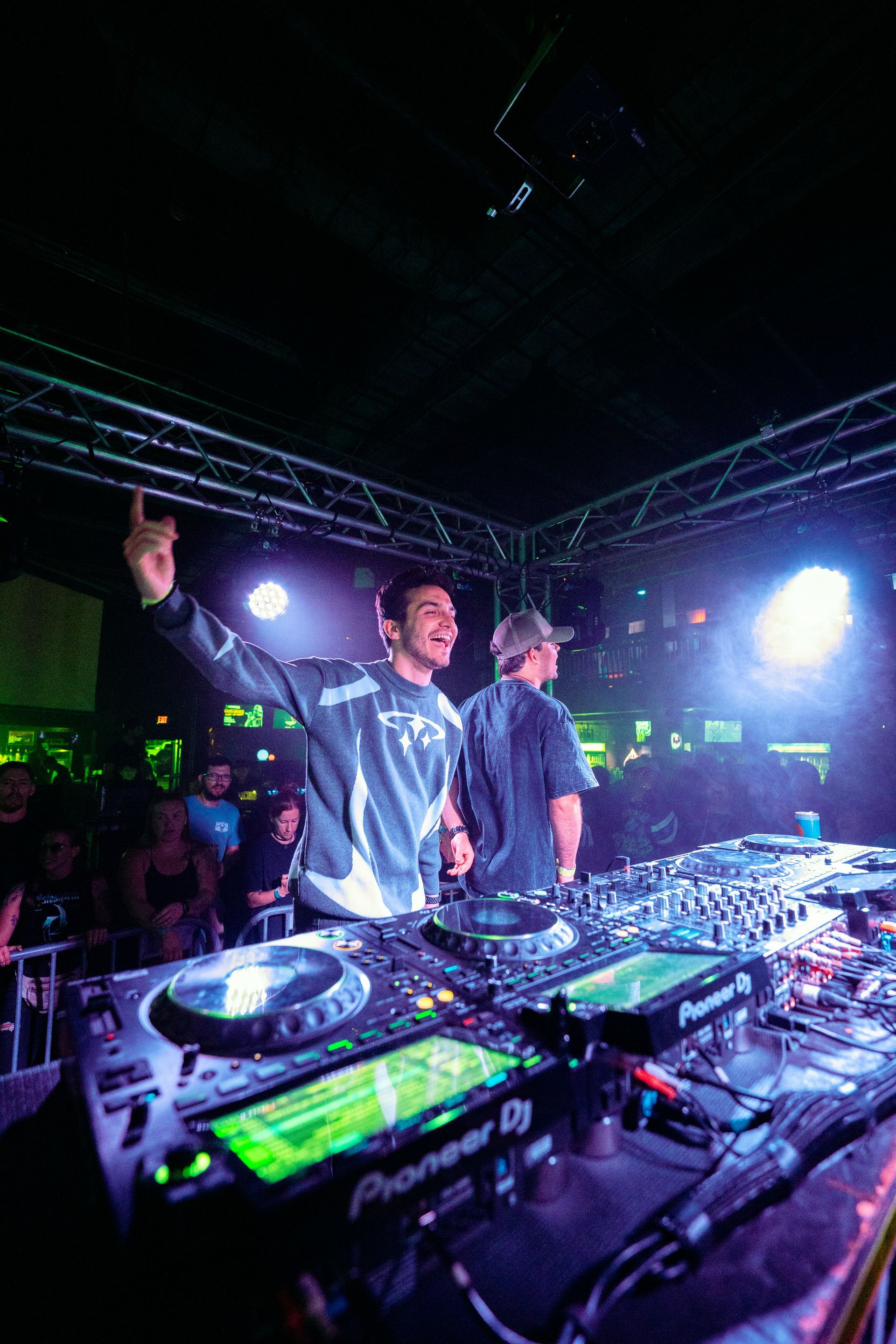 Two men are playing music on a stage in a club.