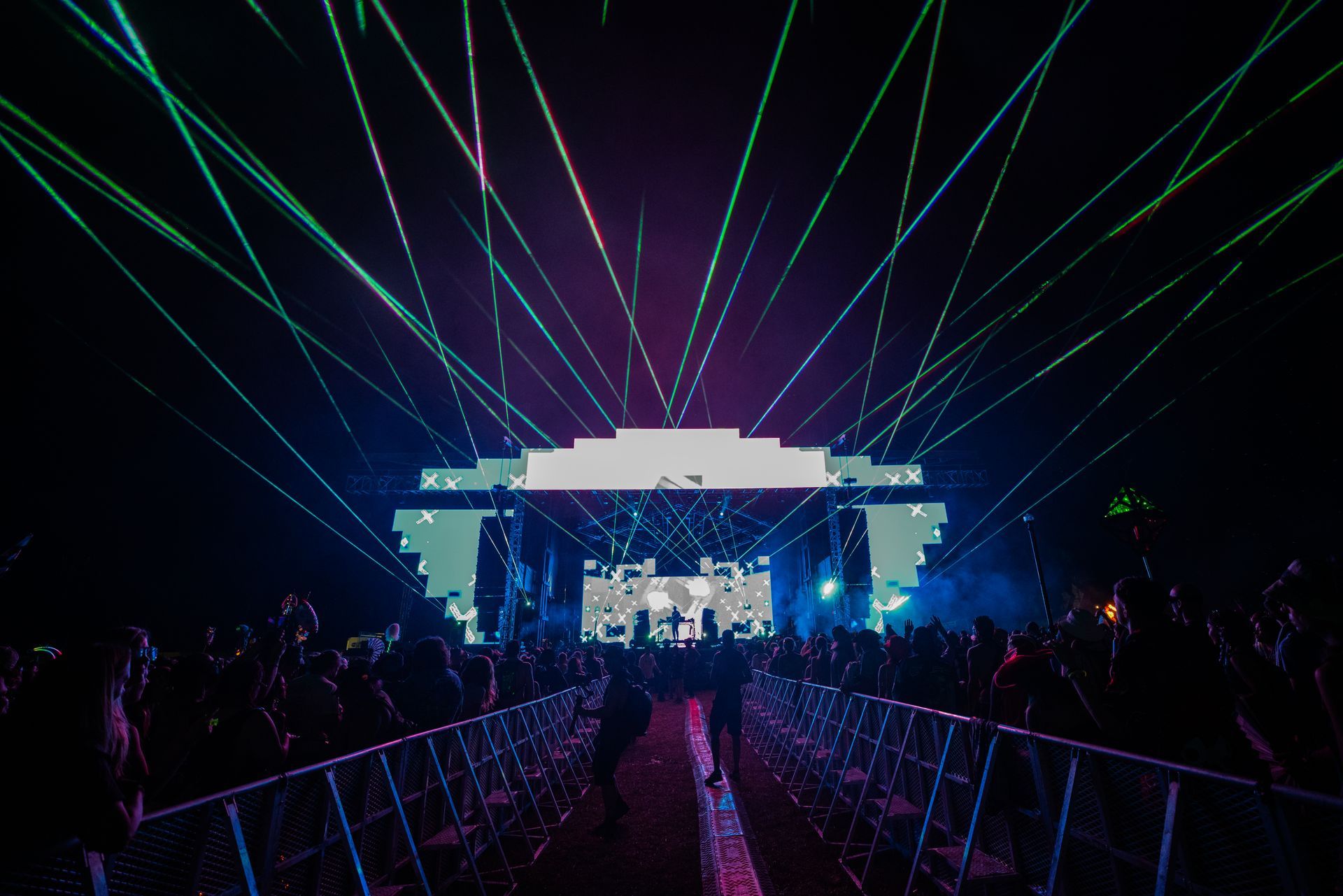 A crowd of people are standing in front of a stage at a concert.