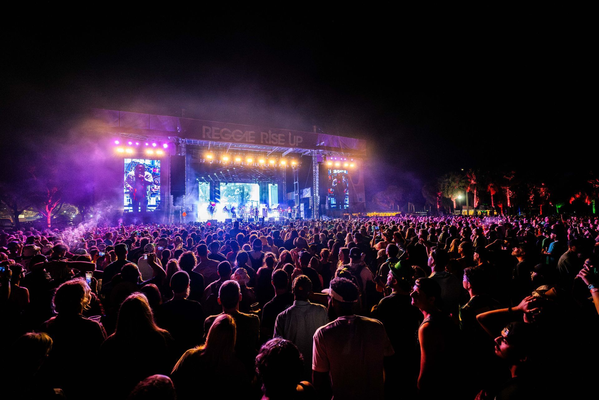 A crowd of people are standing in front of a stage at a concert.