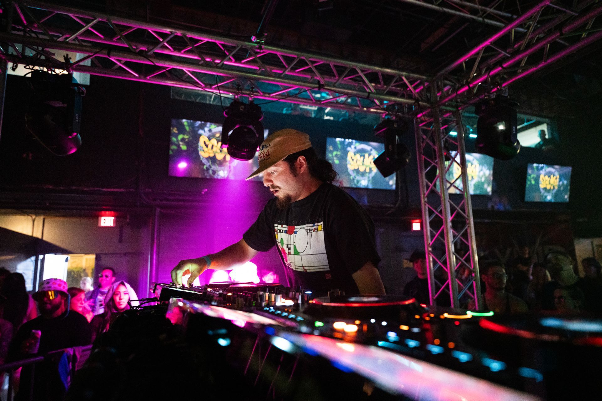 A dj is playing music in front of a crowd in a club.