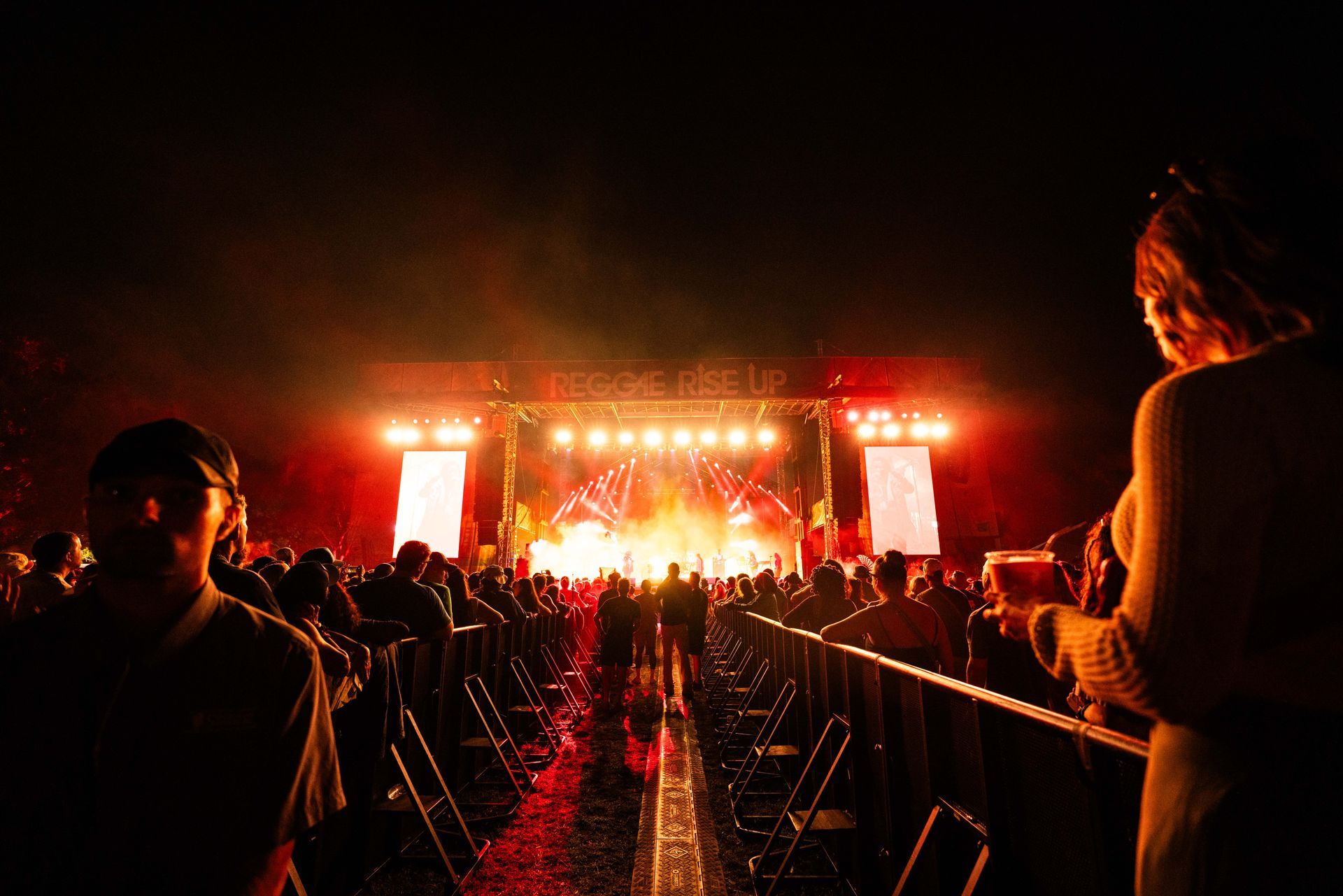 A crowd of people are standing in front of a stage at a concert.