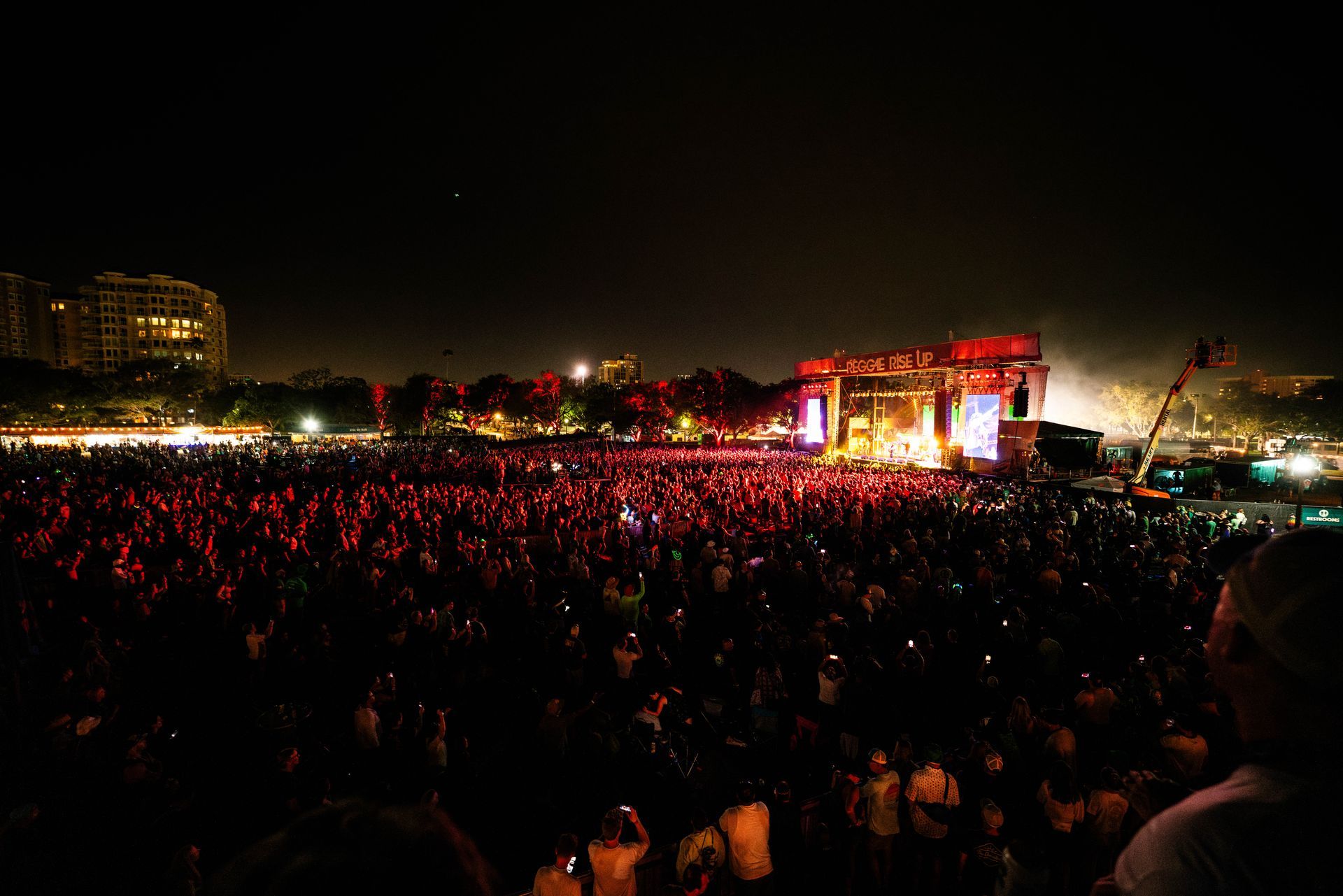A large crowd of people are watching a concert at night.