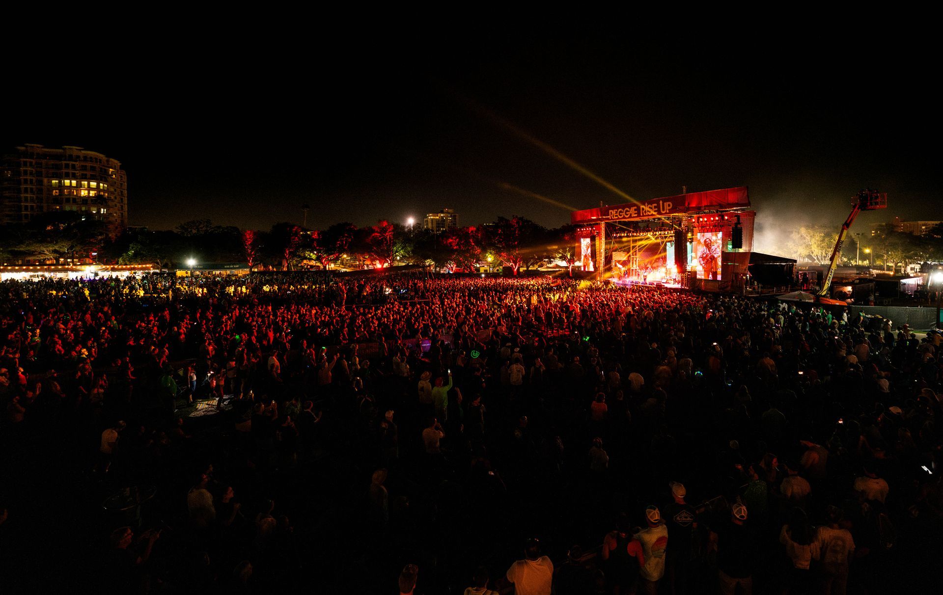 A large crowd of people are watching a concert at night.