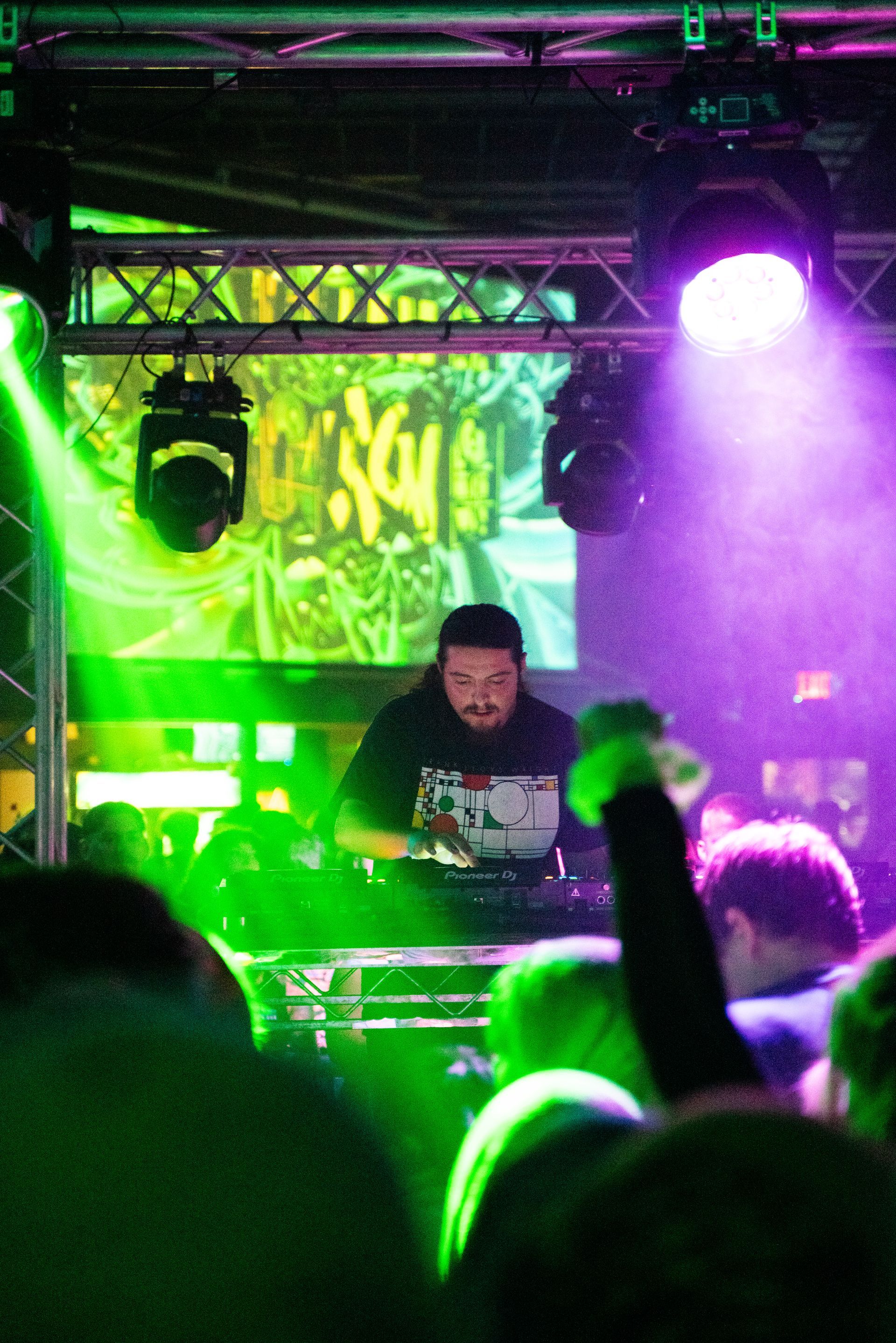 A man is playing music on a laptop in front of a crowd at a concert.