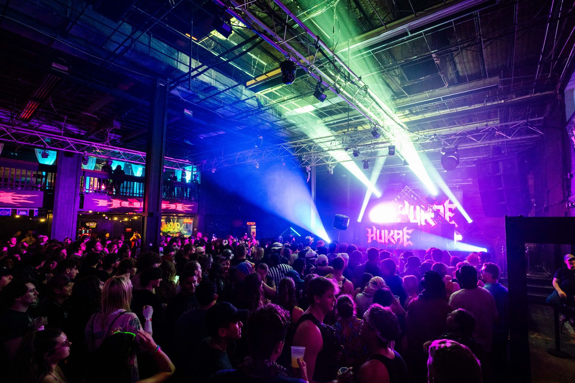 A crowd of people are gathered in a dark room at a concert.
