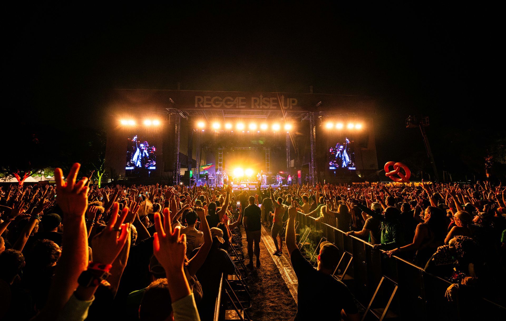 A crowd of people at a concert with their hands in the air