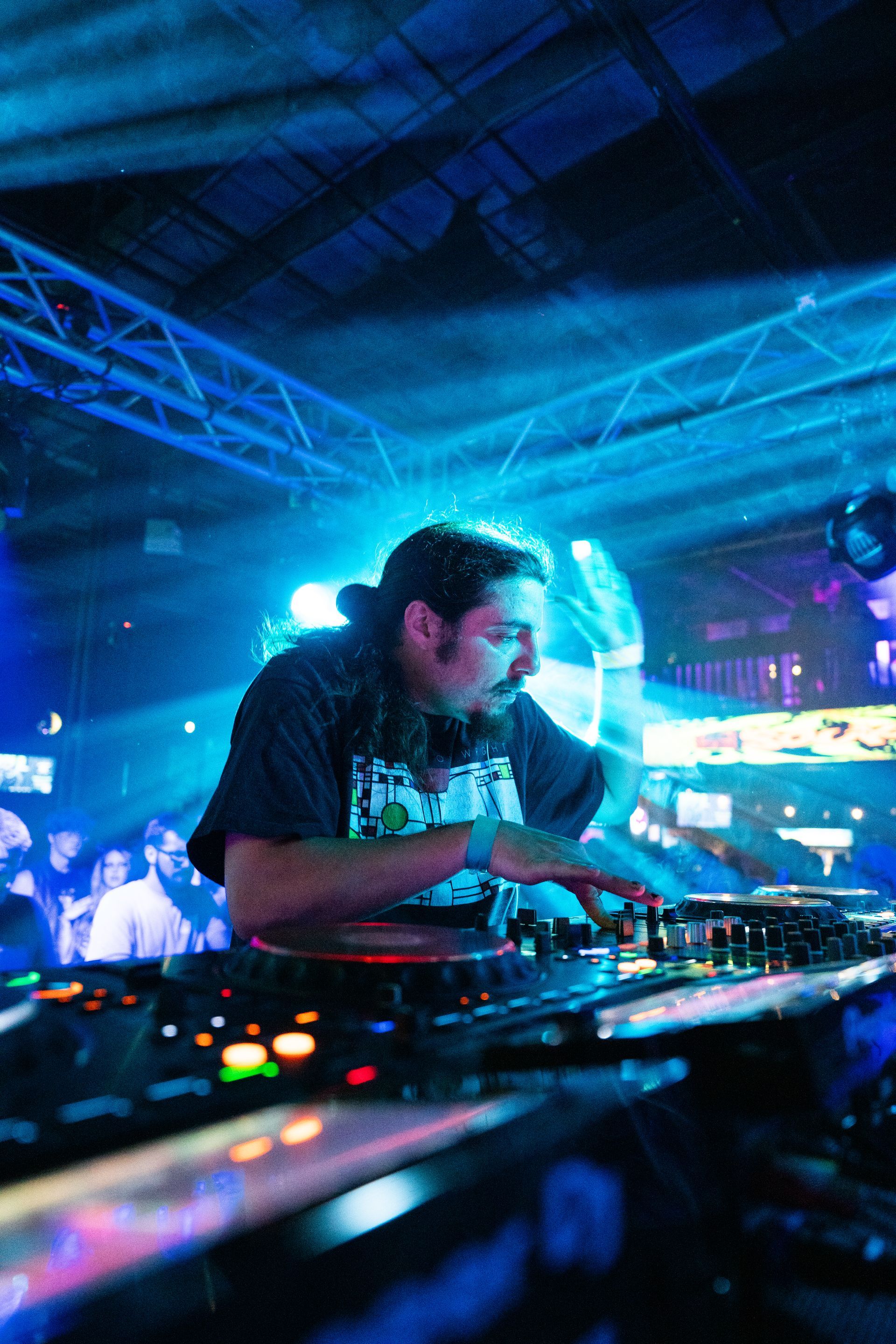A dj is playing music in a dark room with blue lights
