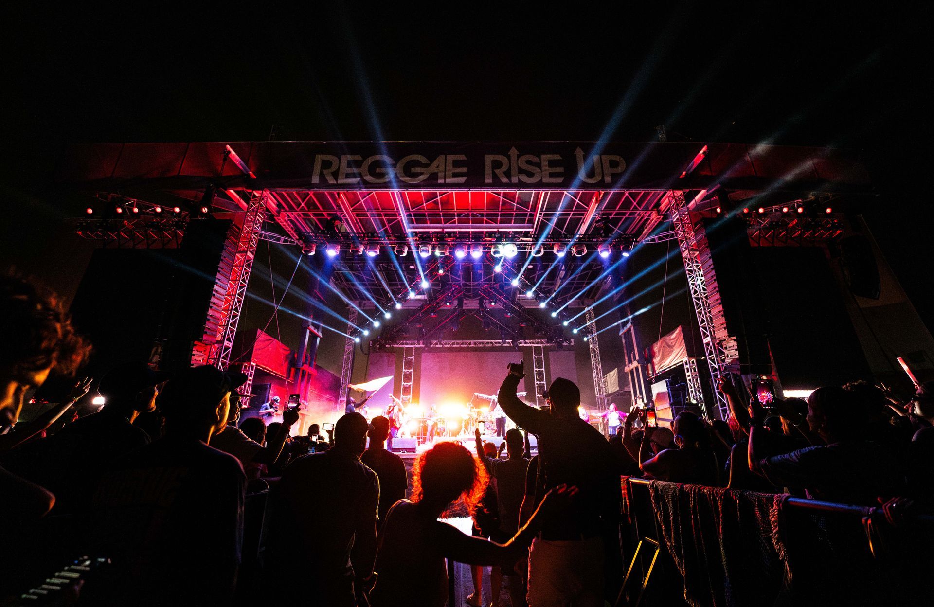 A crowd of people are standing in front of a stage at a concert.