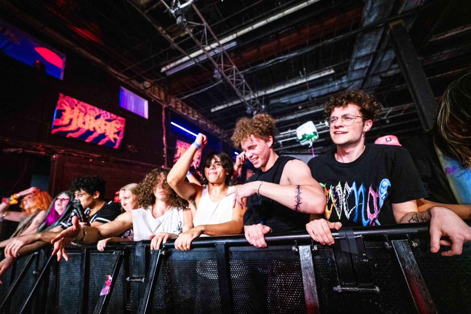 A group of people are standing behind a fence at a concert.