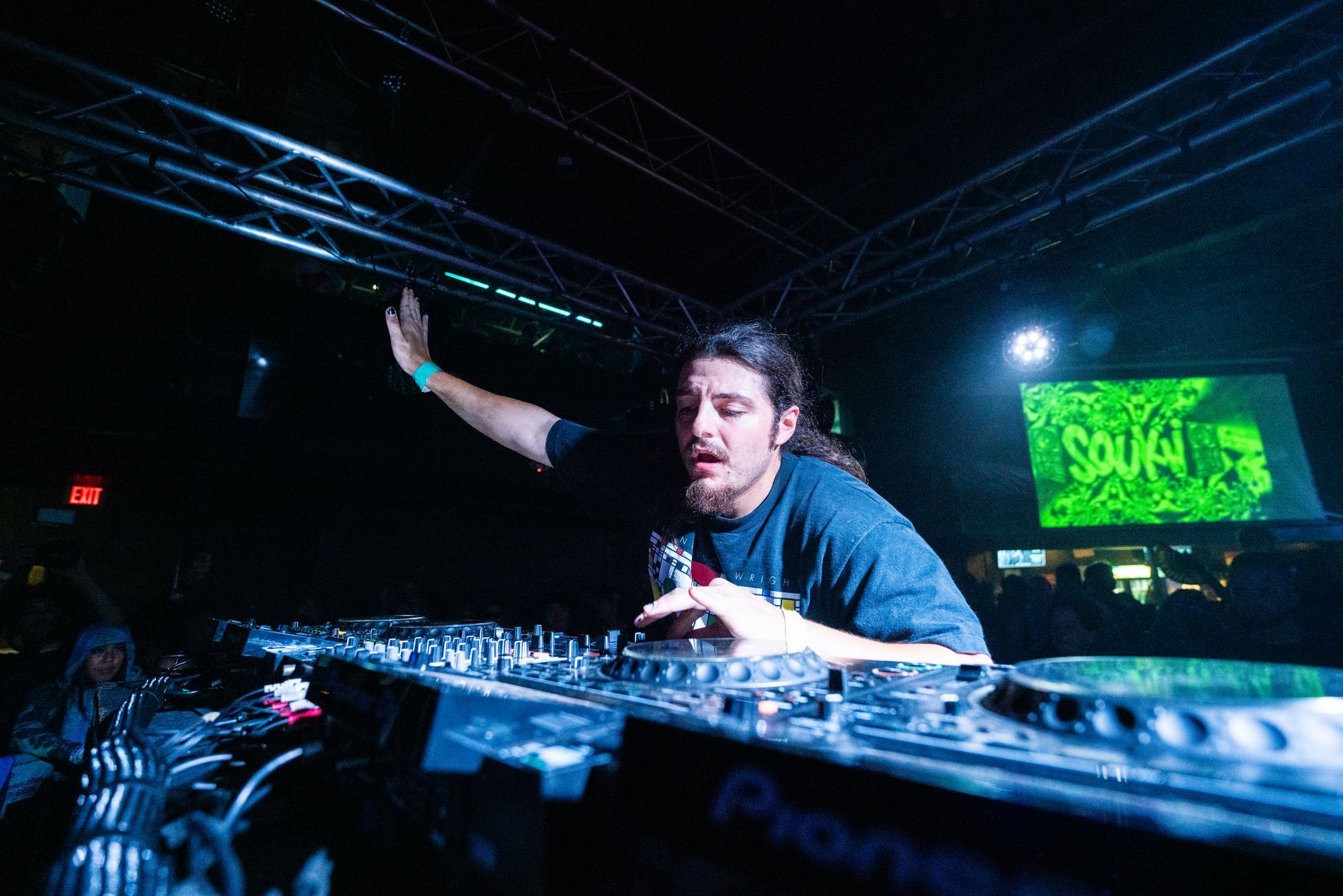 A man is playing a dj set in a dark room.