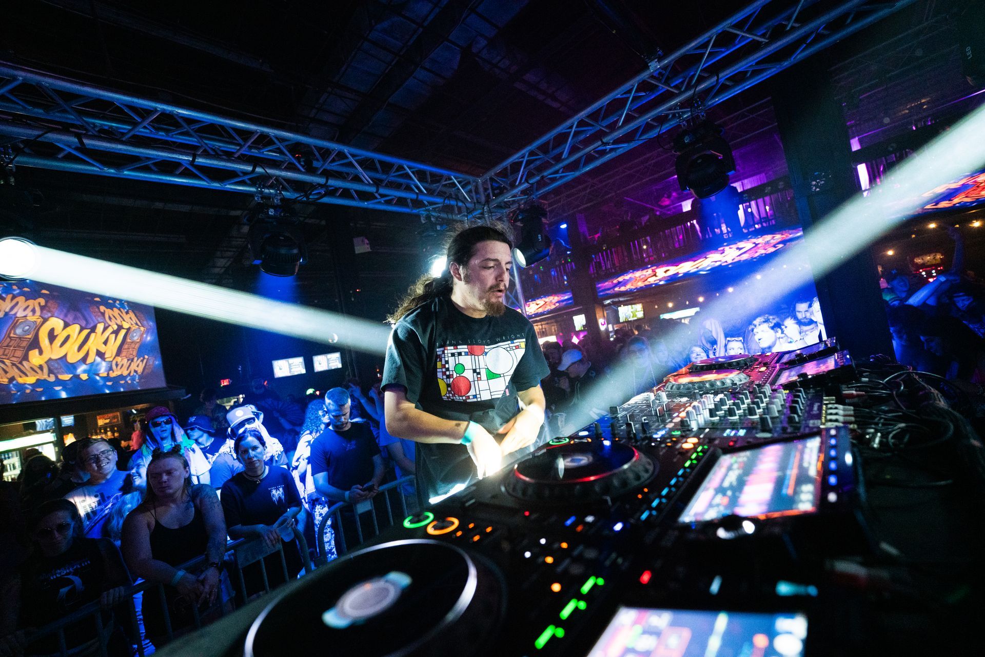 A dj is playing music in front of a crowd at a club