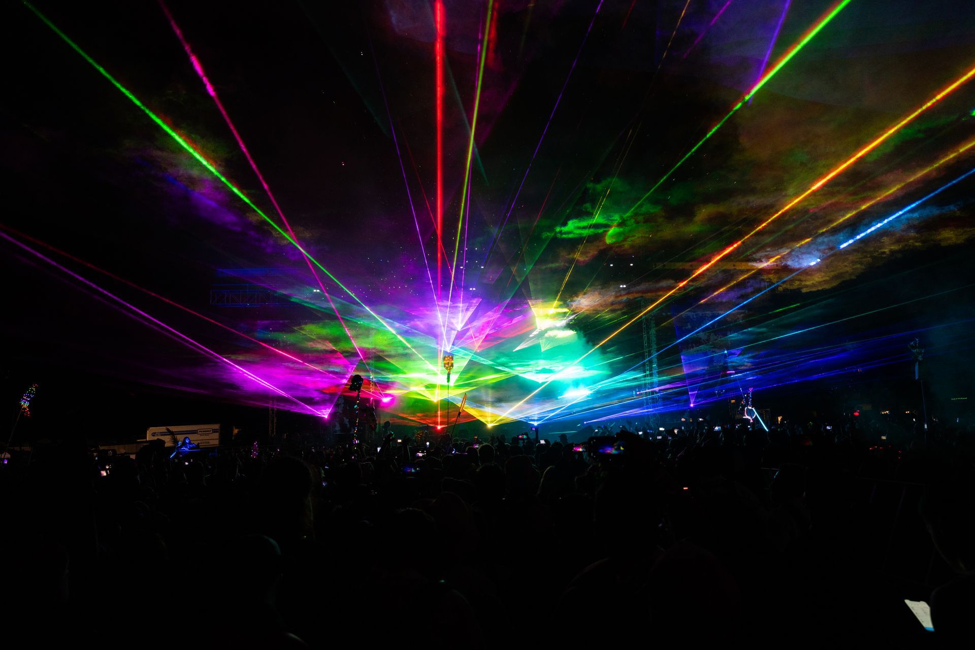 A crowd of people are watching a laser show at a concert.