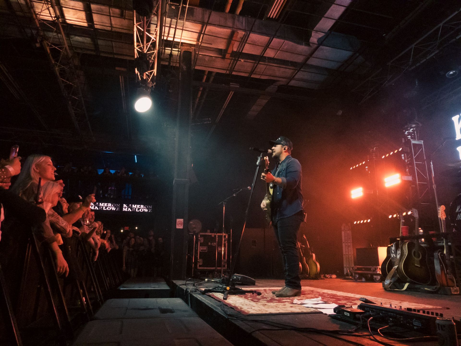A man is playing a guitar on a stage in front of a crowd.