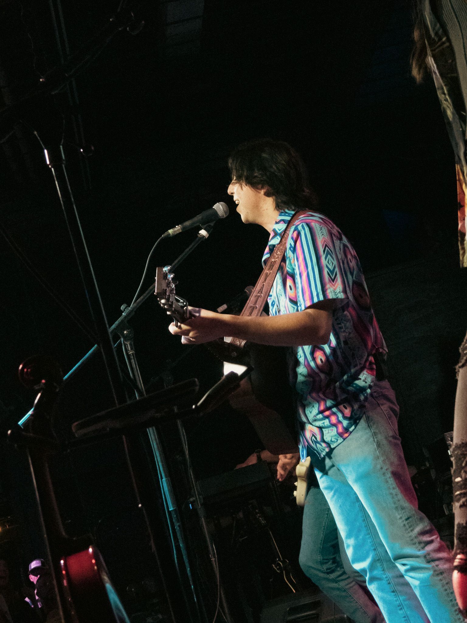 A man singing into a microphone while playing a guitar