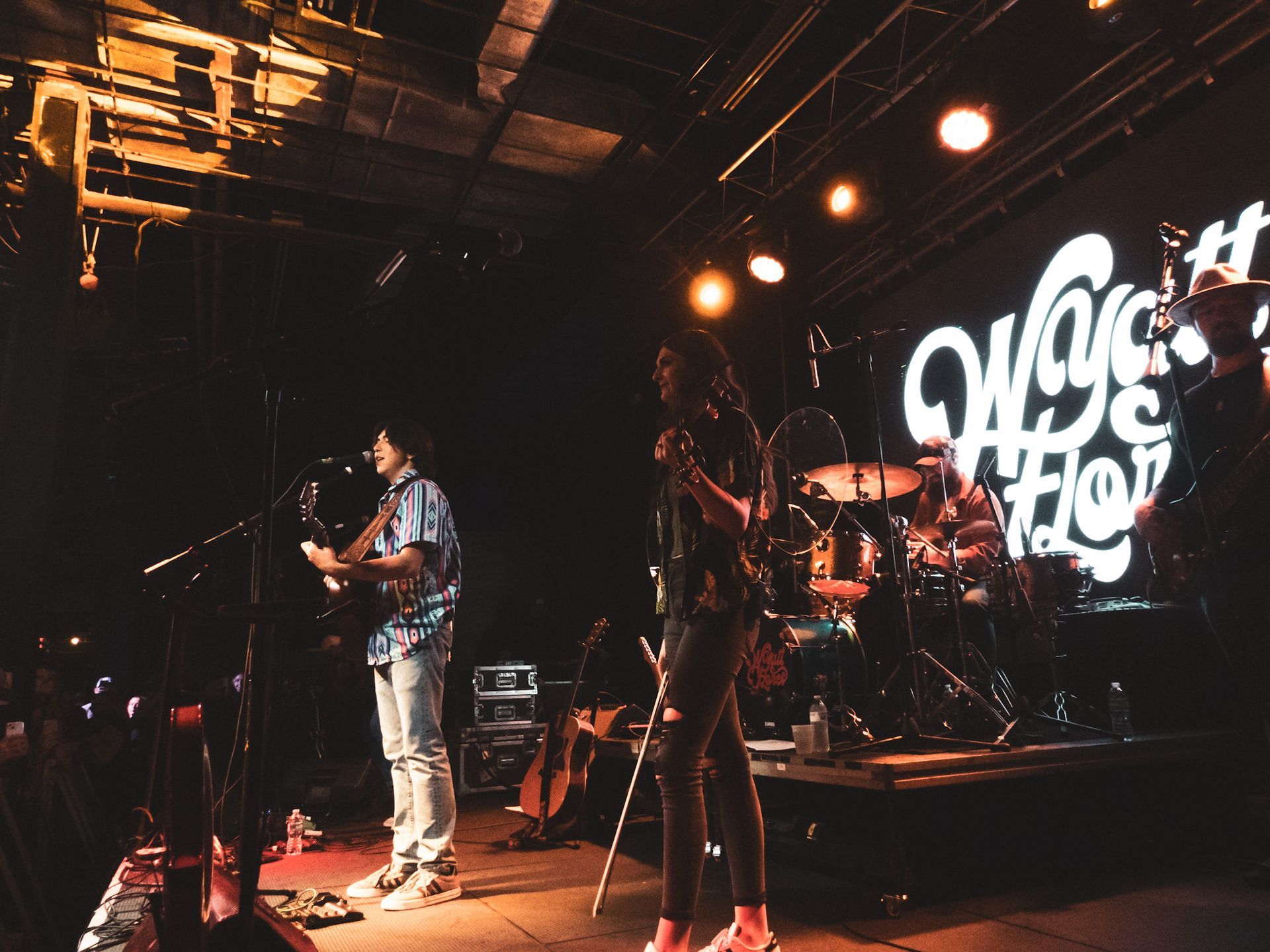 A group of people are playing instruments on a stage in a dark room.