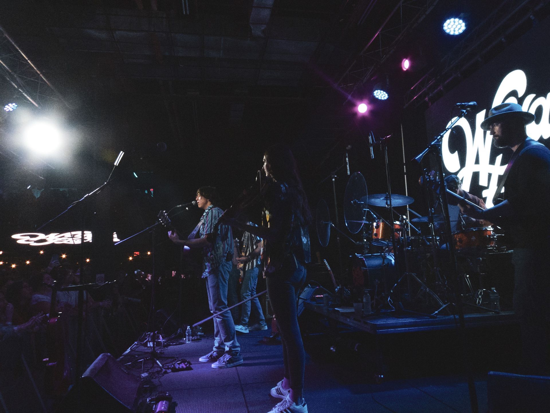 A group of people are playing instruments on a stage in a dark room.