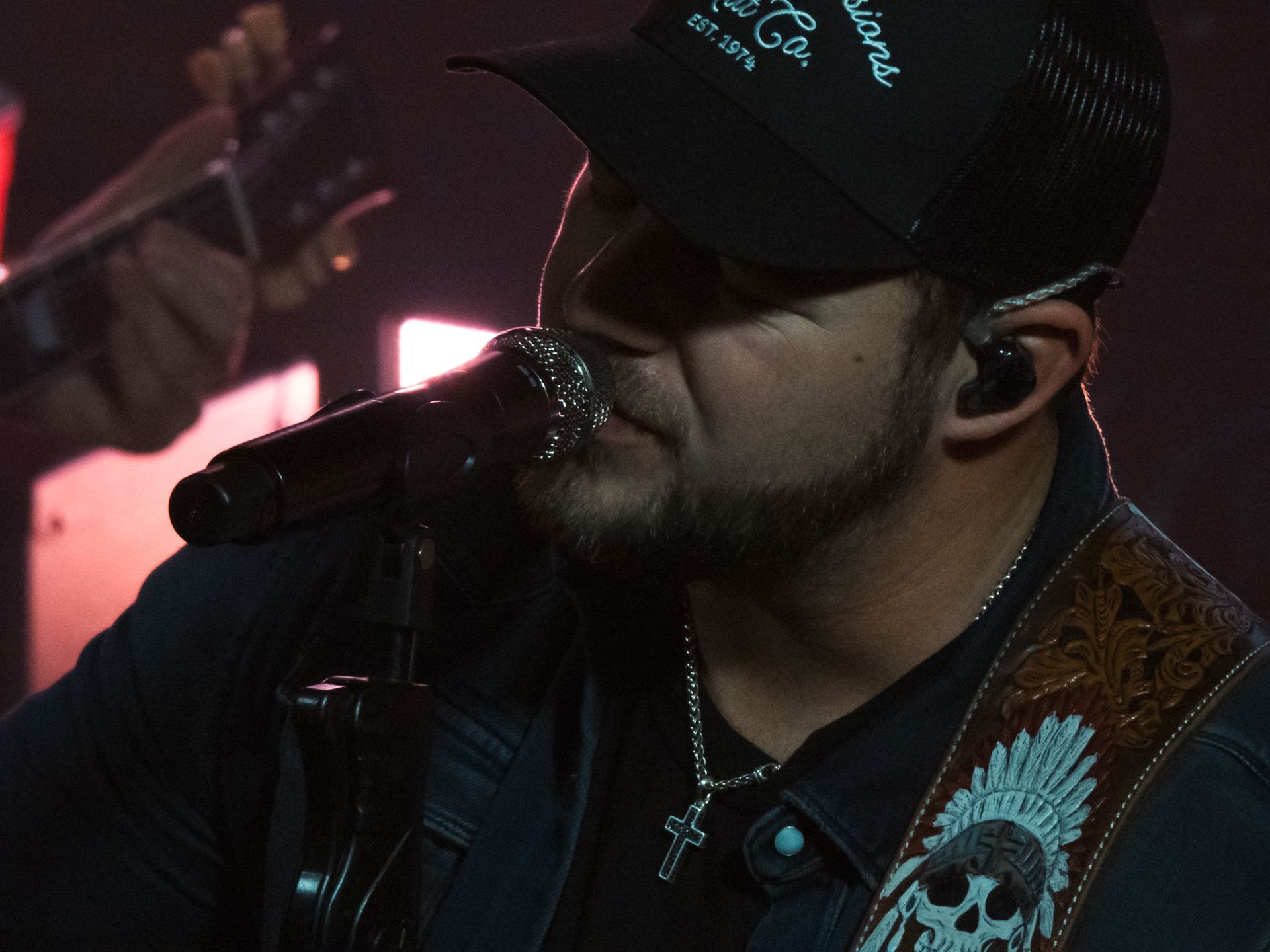 A man singing into a microphone while wearing a hat that says louisiana