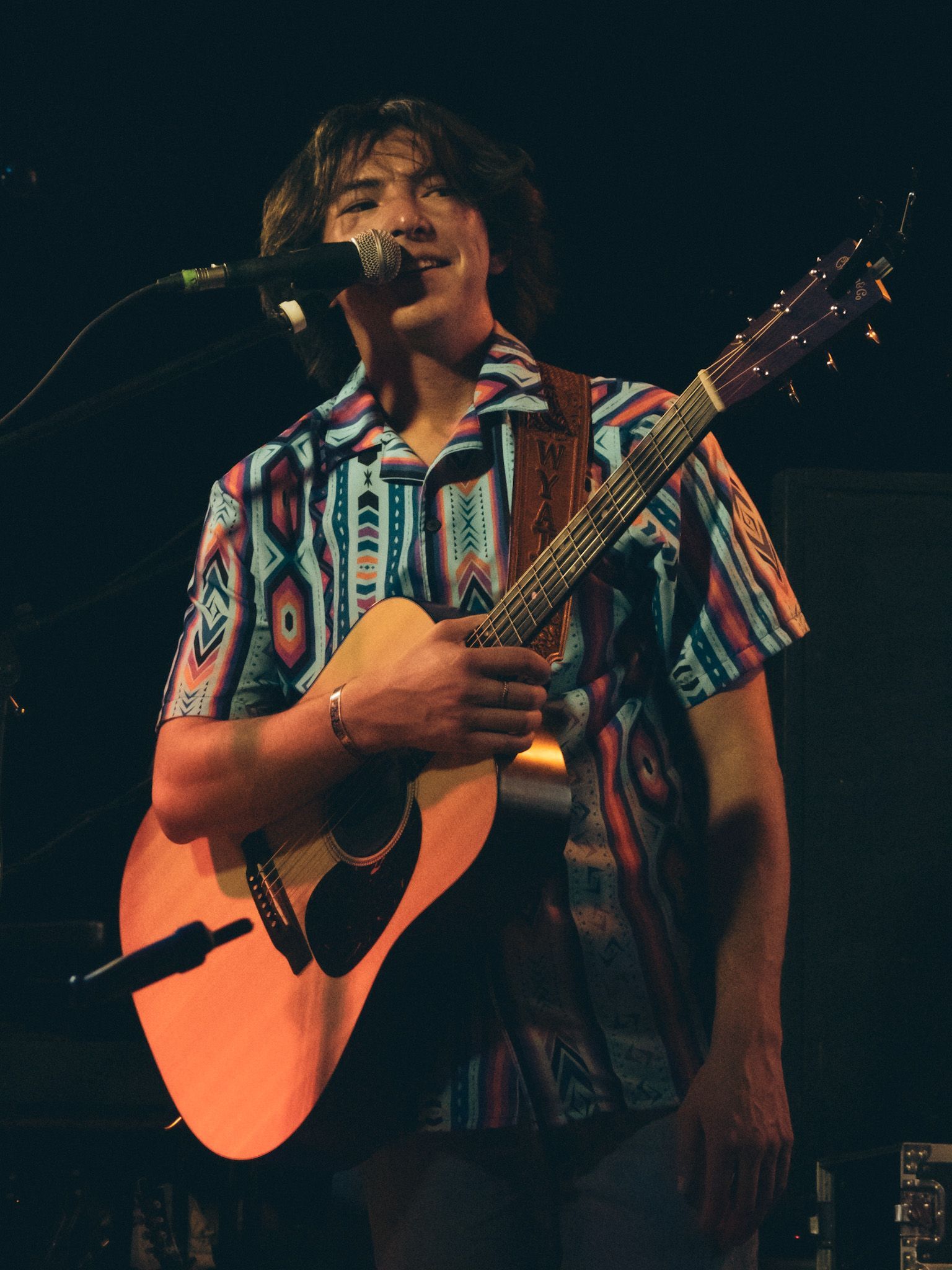 A man singing into a microphone while holding a guitar