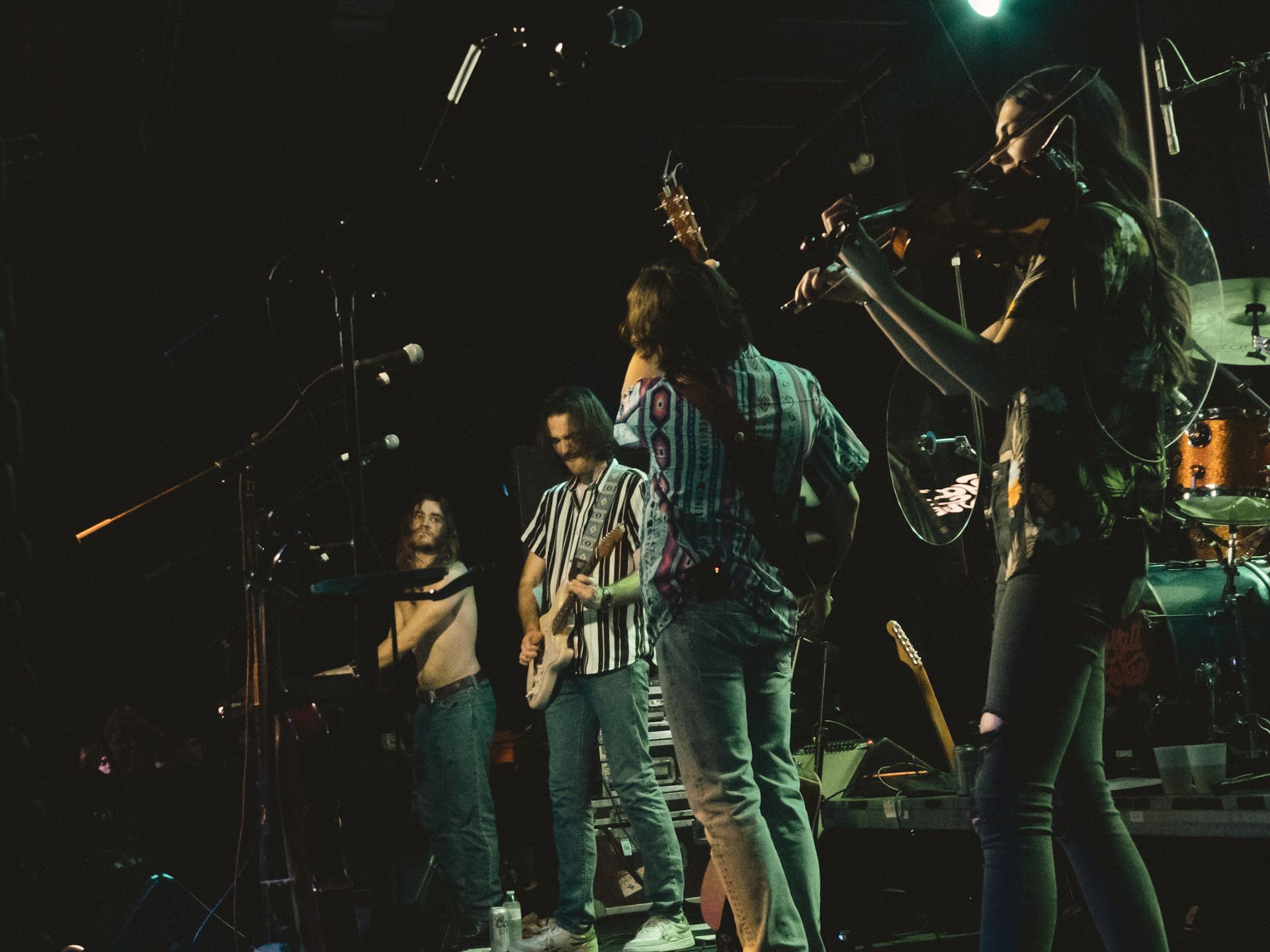 A group of people are playing instruments on a stage in a dark room.