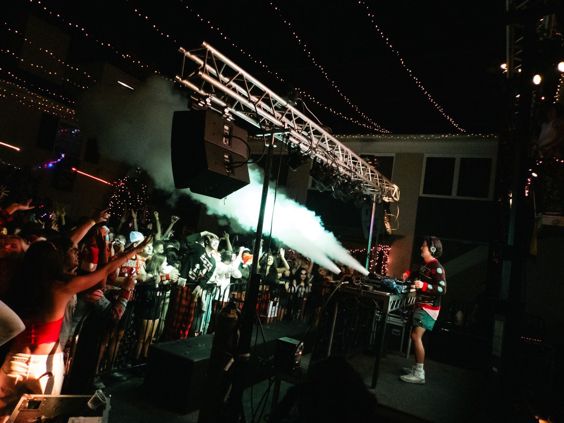 A group of people are standing in front of a stage with smoke coming out of it.