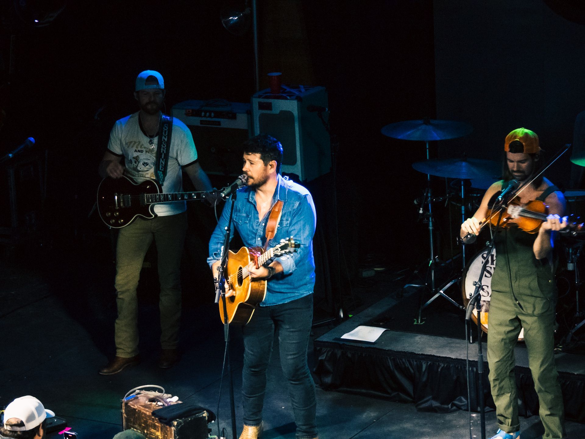 A man is playing a guitar and a man is playing a violin on stage.