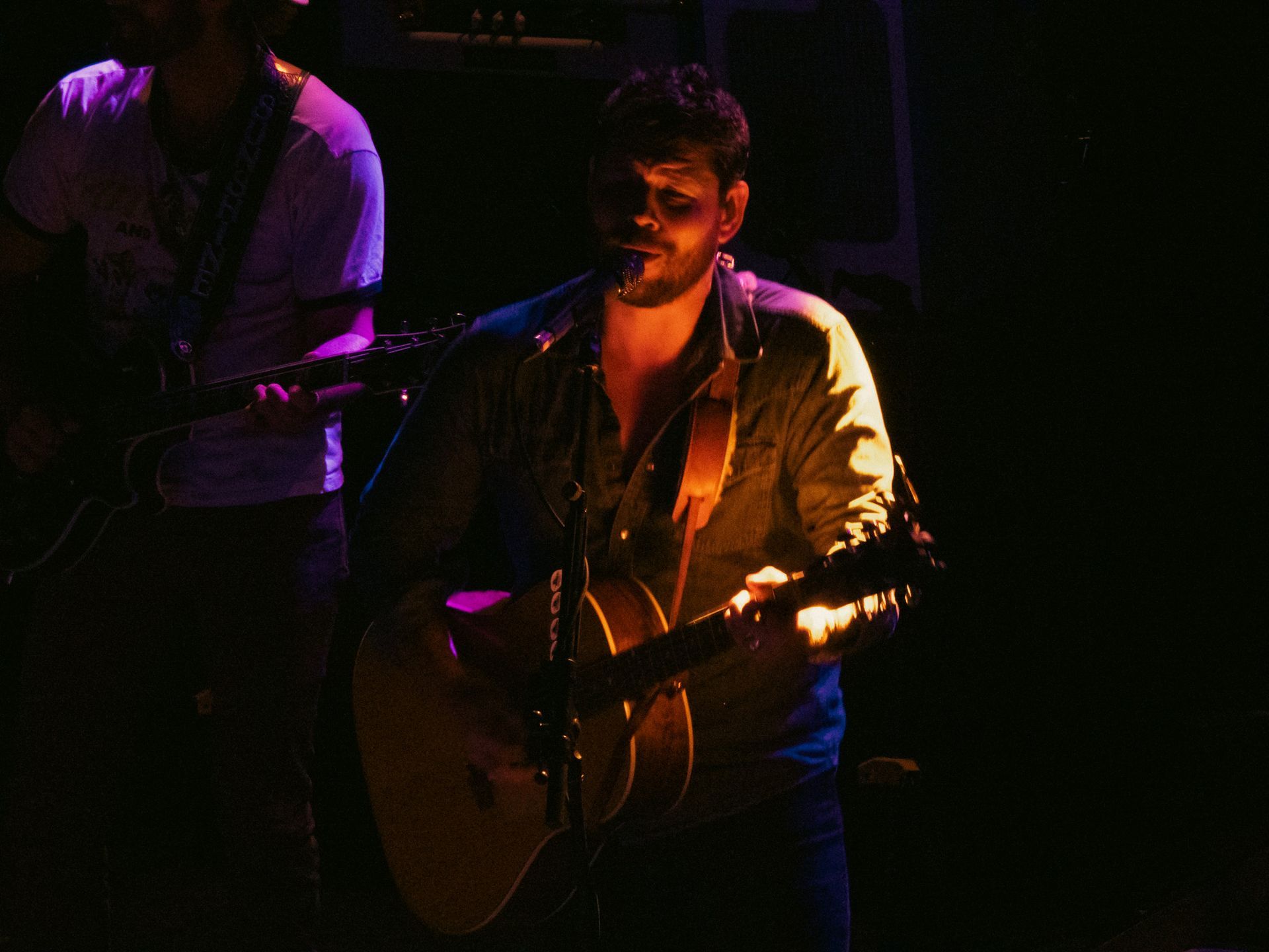 A man singing into a microphone while playing a guitar