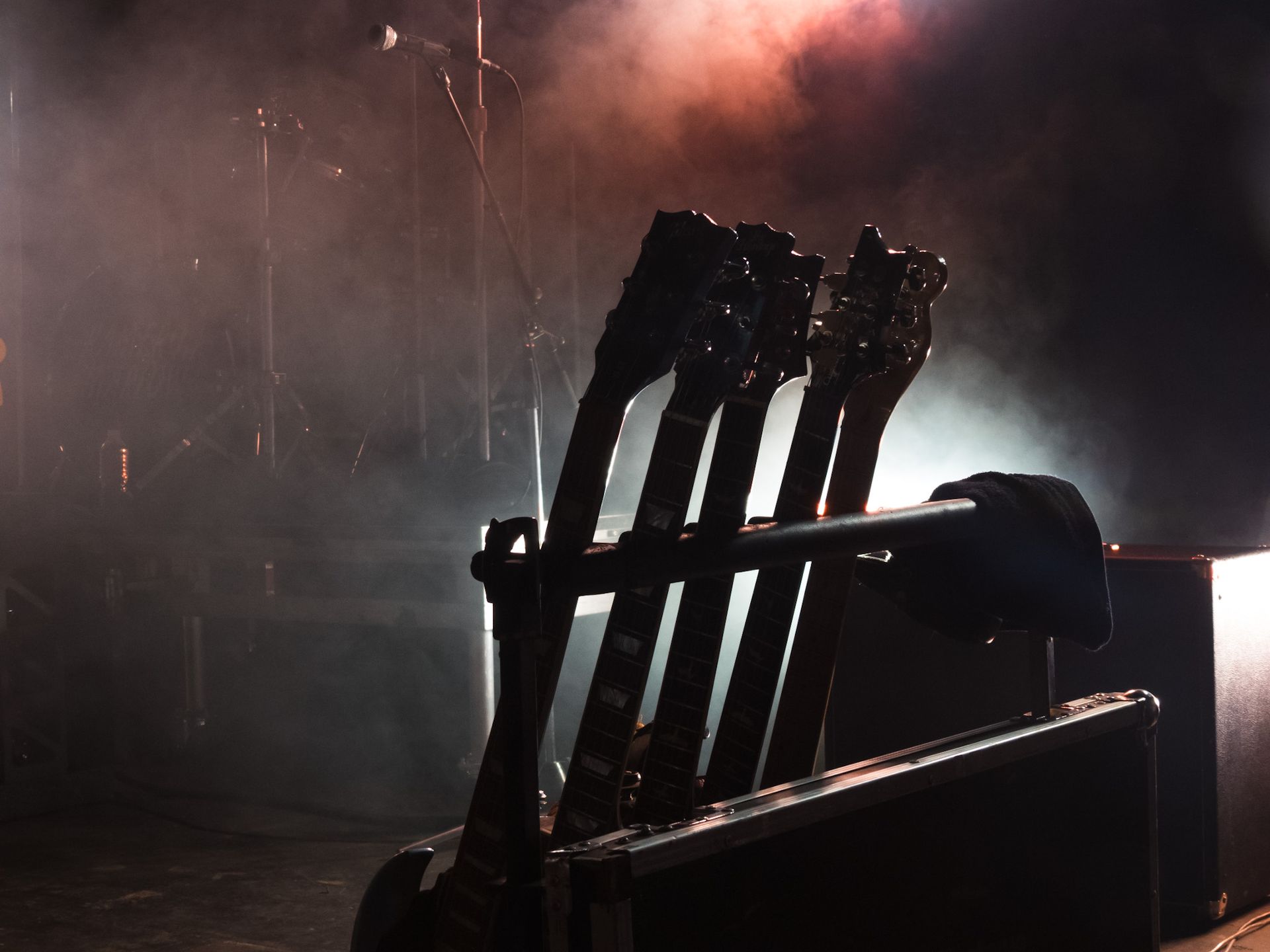 A row of guitars sitting on top of a case on a stage