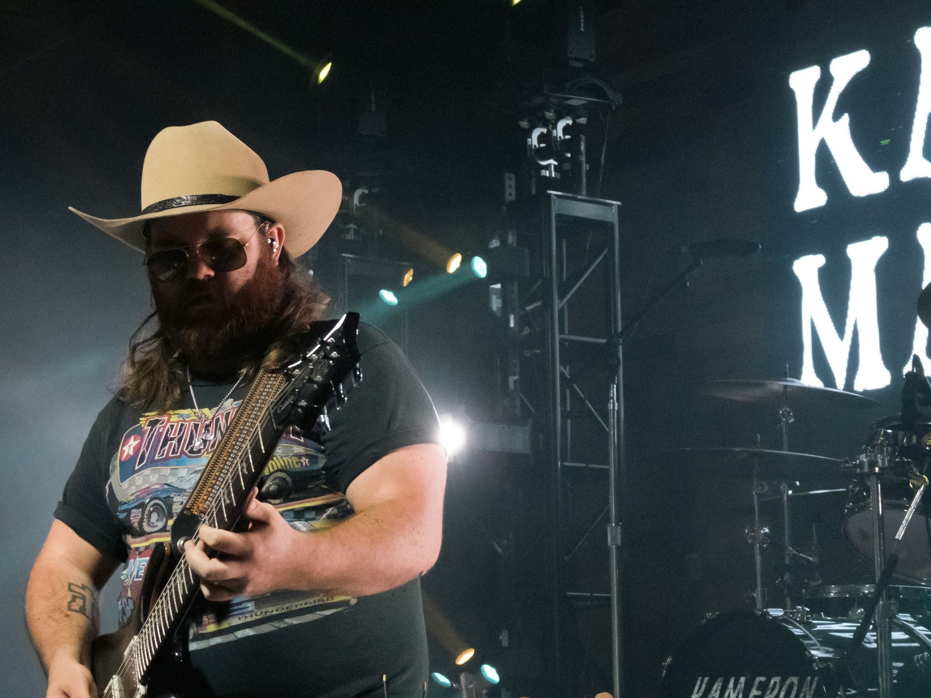 A man in a cowboy hat is playing a guitar