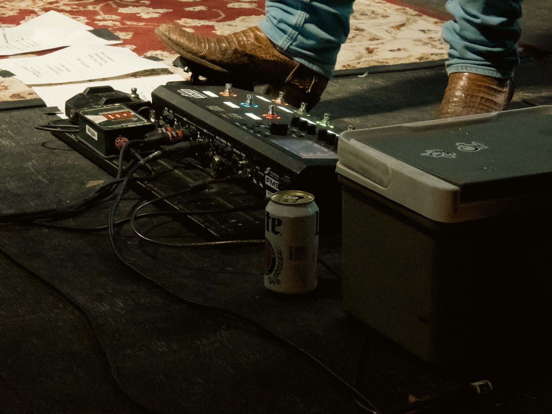 A person 's foot is on a pedal board next to a can of beer