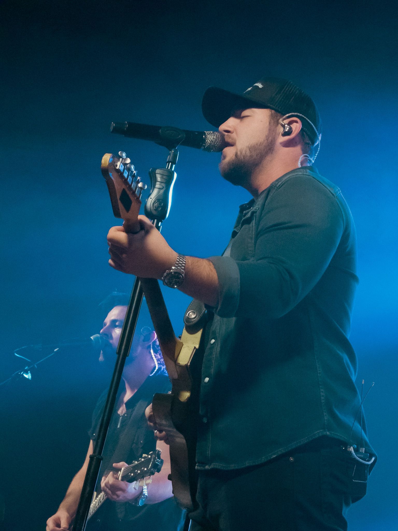 A man singing into a microphone while holding a guitar