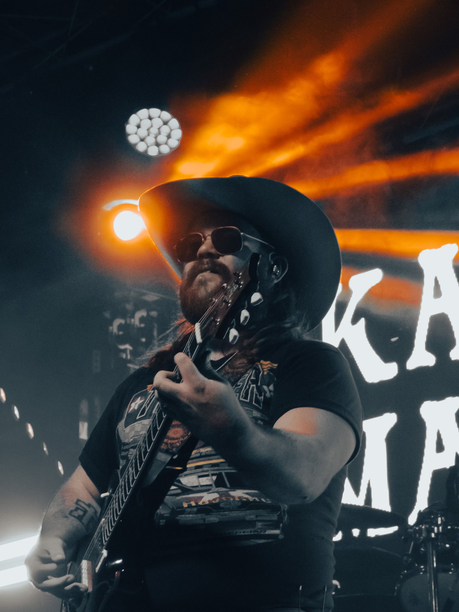 A man in a cowboy hat is playing a guitar on stage.