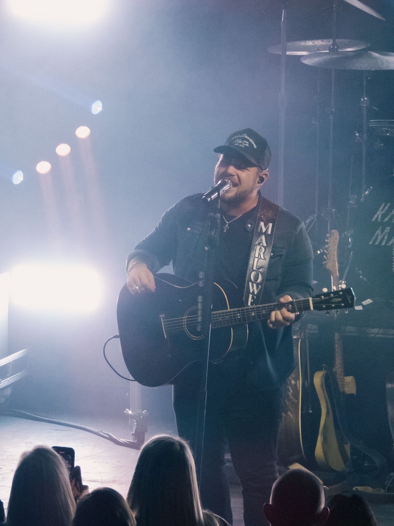 A man is singing into a microphone while playing a guitar on stage.
