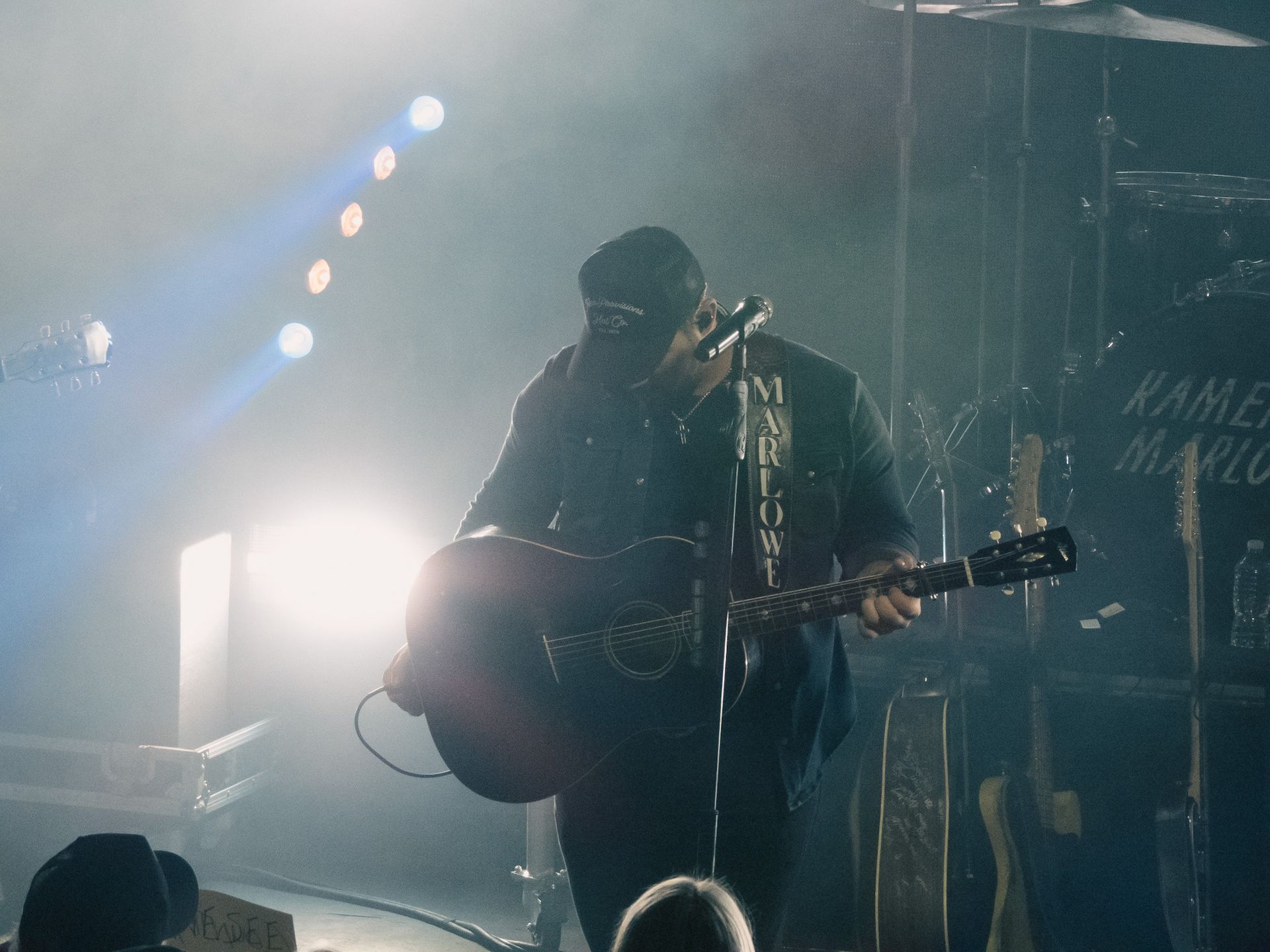 A man is playing a guitar and singing into a microphone on a stage.