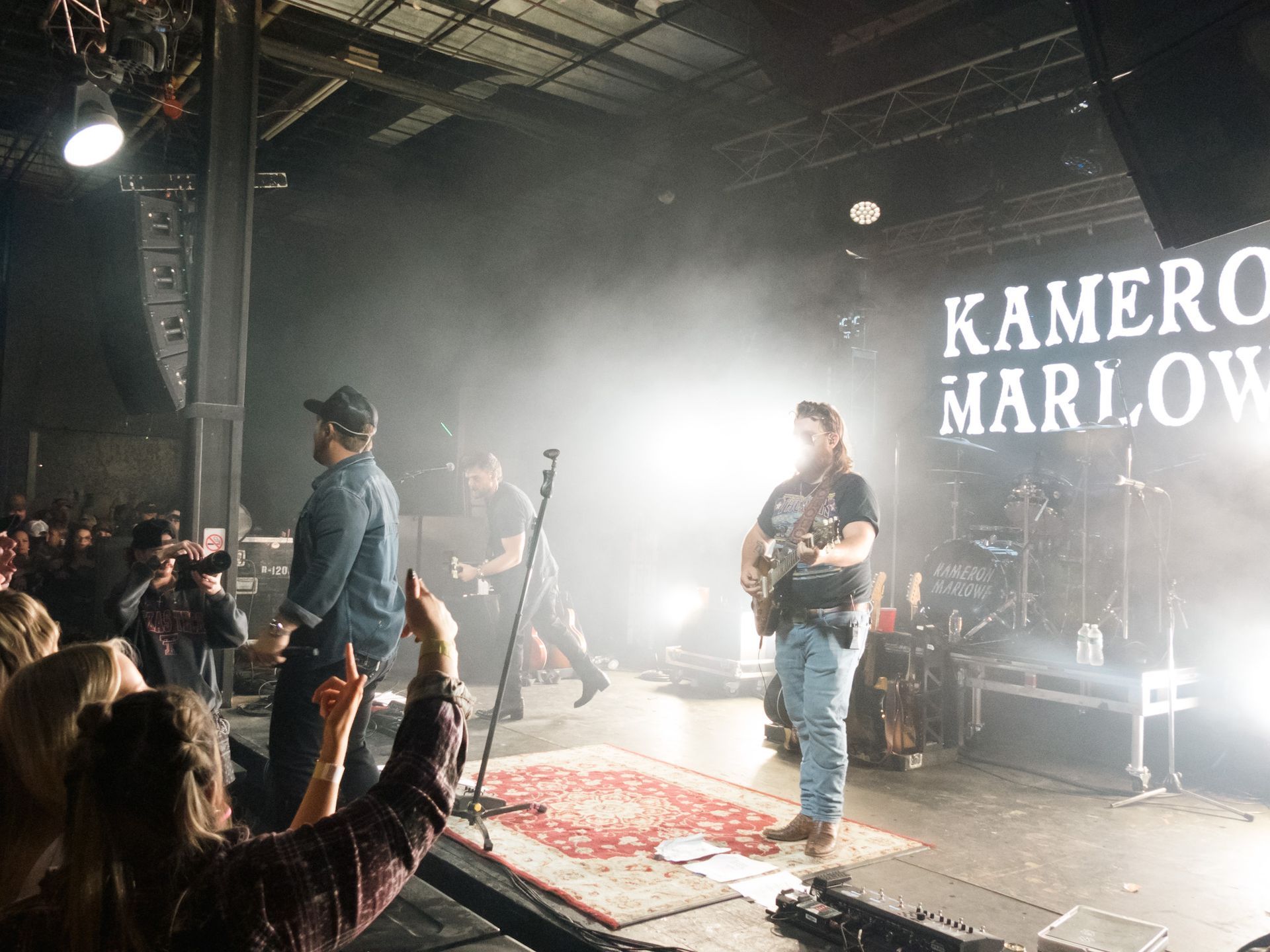 A group of people are standing on a stage in front of a sign that says kamera marlow.